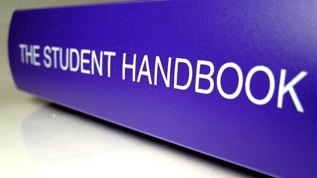 Close-up of a purple book titled 'The Student Handbook'