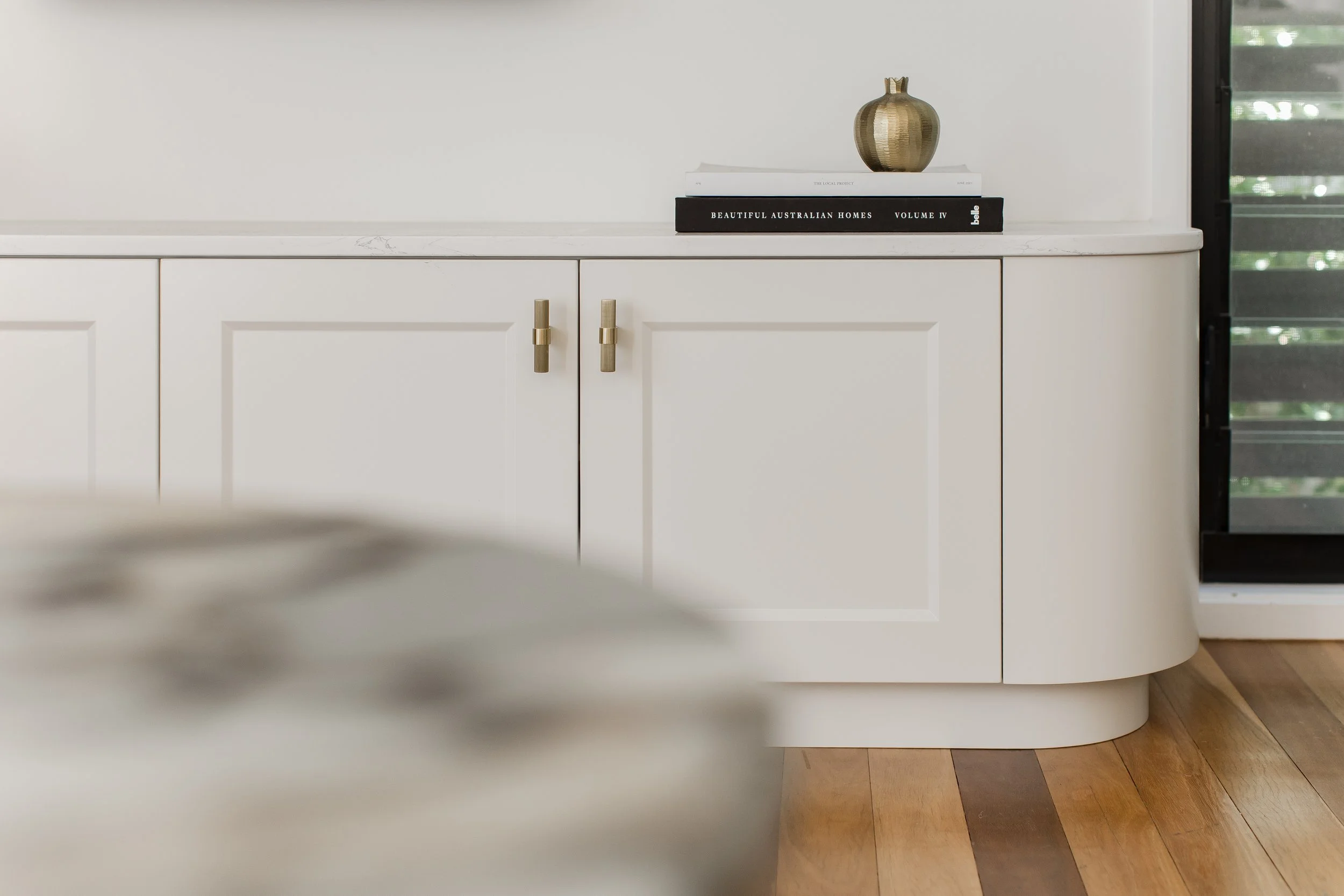 Custom white joinery with brushed brass hardware and marble splashback in a Brisbane residential interior by Arc + Arlo