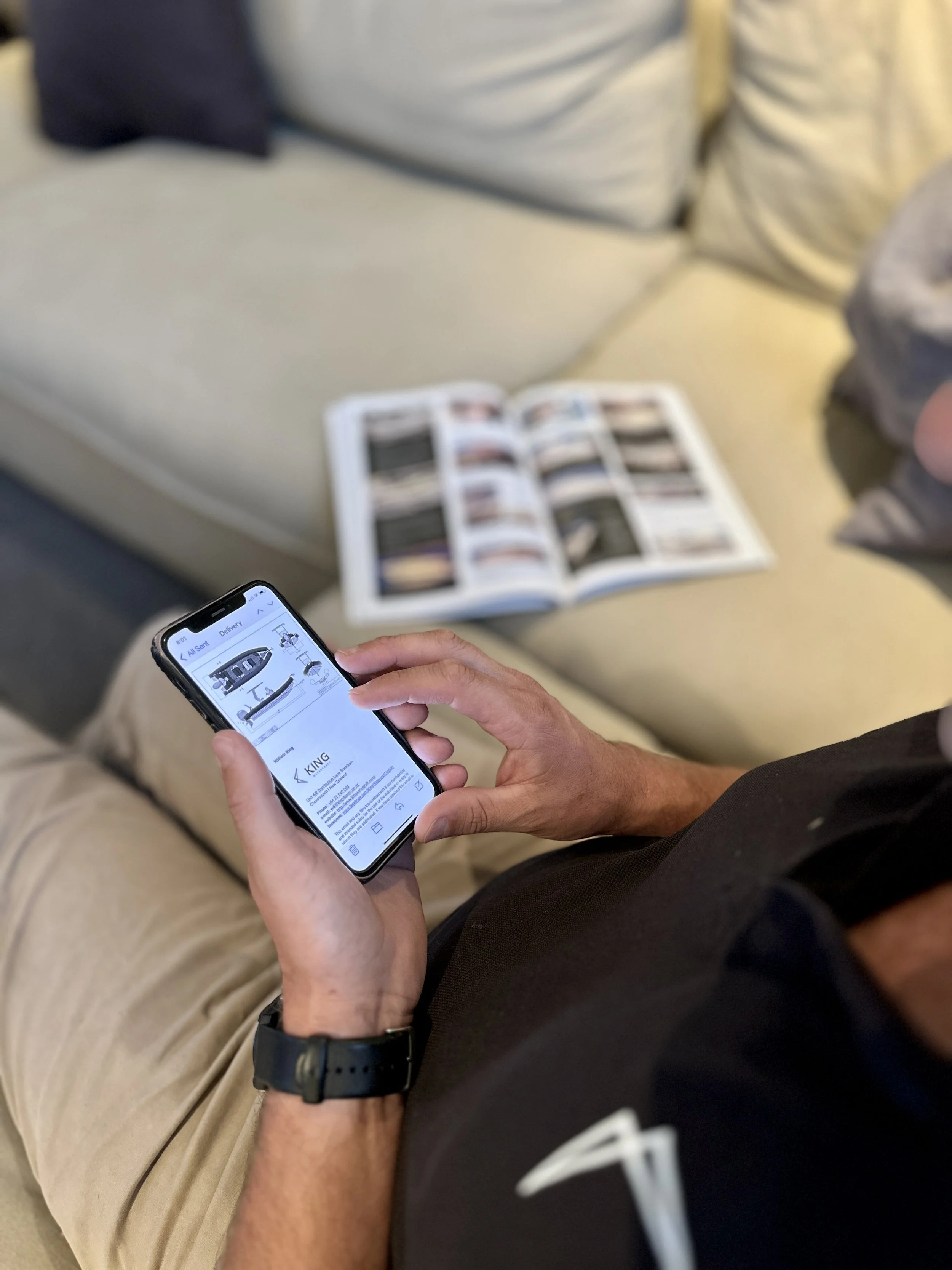 person holding Iphone reading emails next to magazine