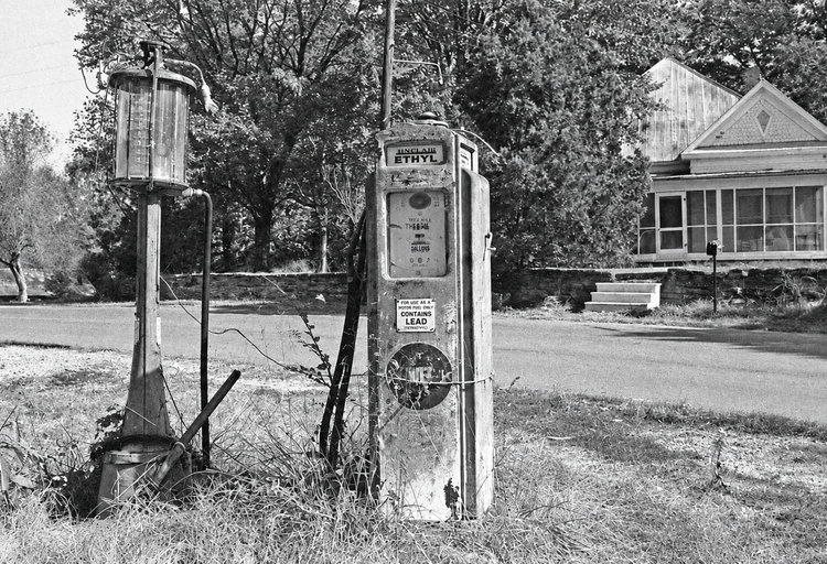 Historic gas pumps with the Landress home across the road in Luxomni