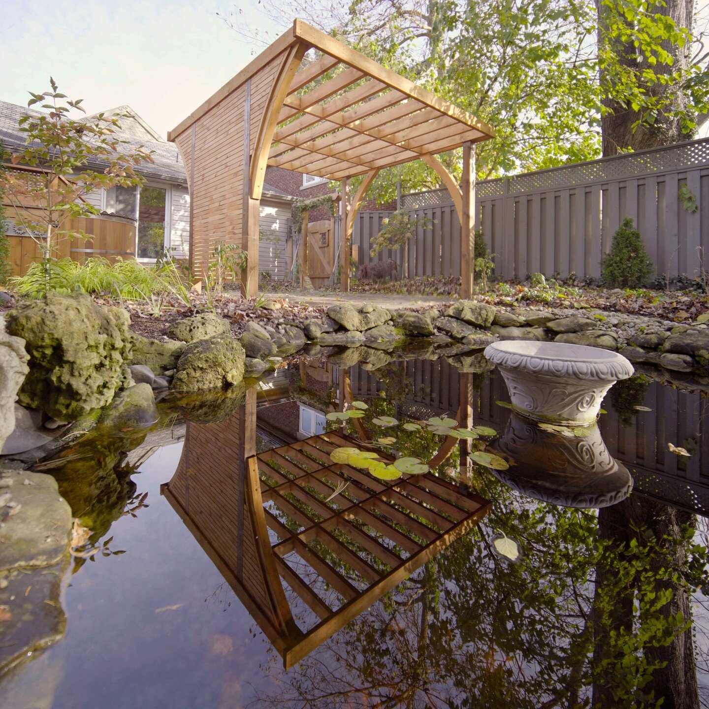 So you want shade for summer dinners on the patio. But you don't want to block the view of your wonderful pond, hot tub and backyard. This white pine pergola uses careful design and giant arches to do both. The curves and white pine texture complemen