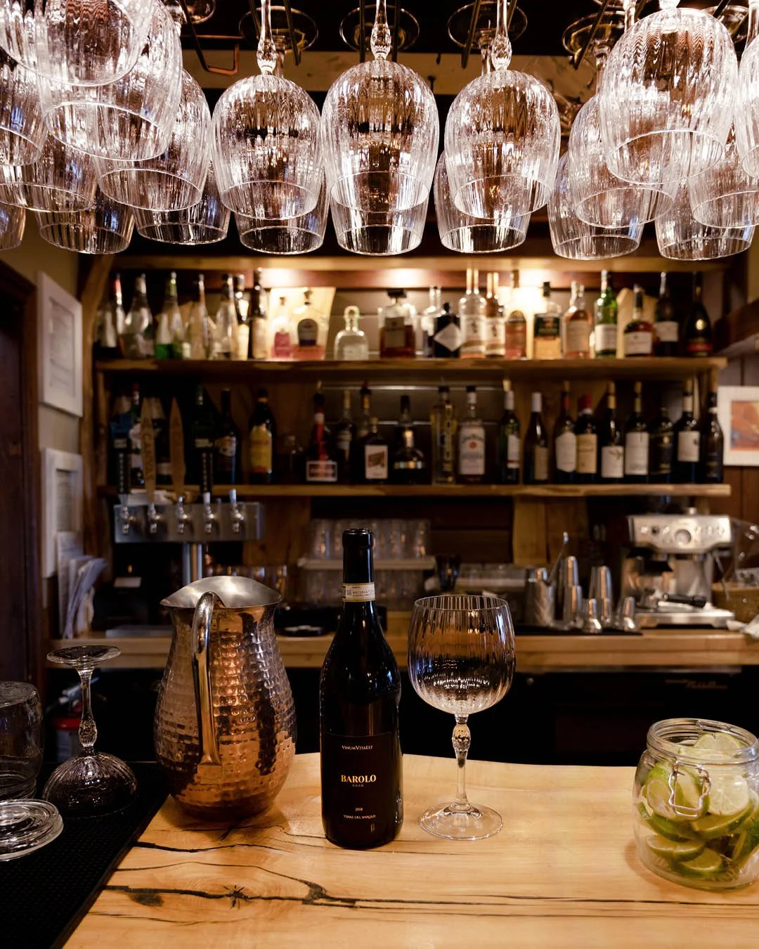 Beneath the soft shimmer of glass and spirits, a bottle of Barolo waits to be opened. 🍷

This deep, ruby-red wine is both elegant and refined. It offers notes of dried red berries and leafy greens, along with aromas of black plum, floral hints, and 