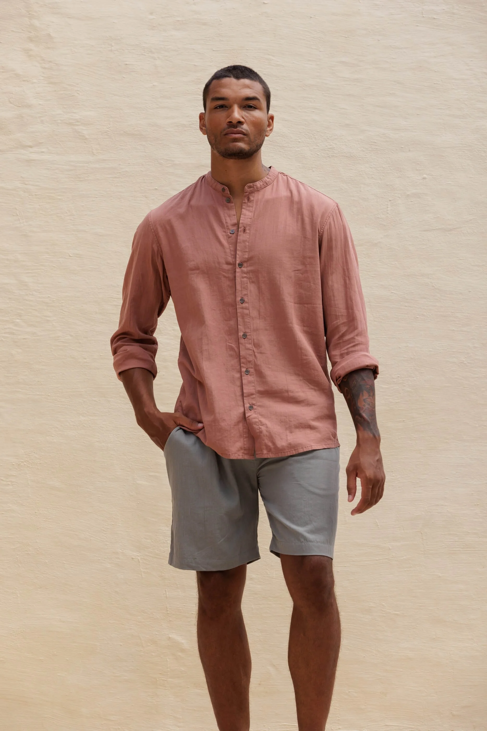 Front view of the model wearing the grey-green Renclì shorts styled with the matching Jordi mandarin collar shirt in terracotta Terra Stone for a complete, relaxed look.