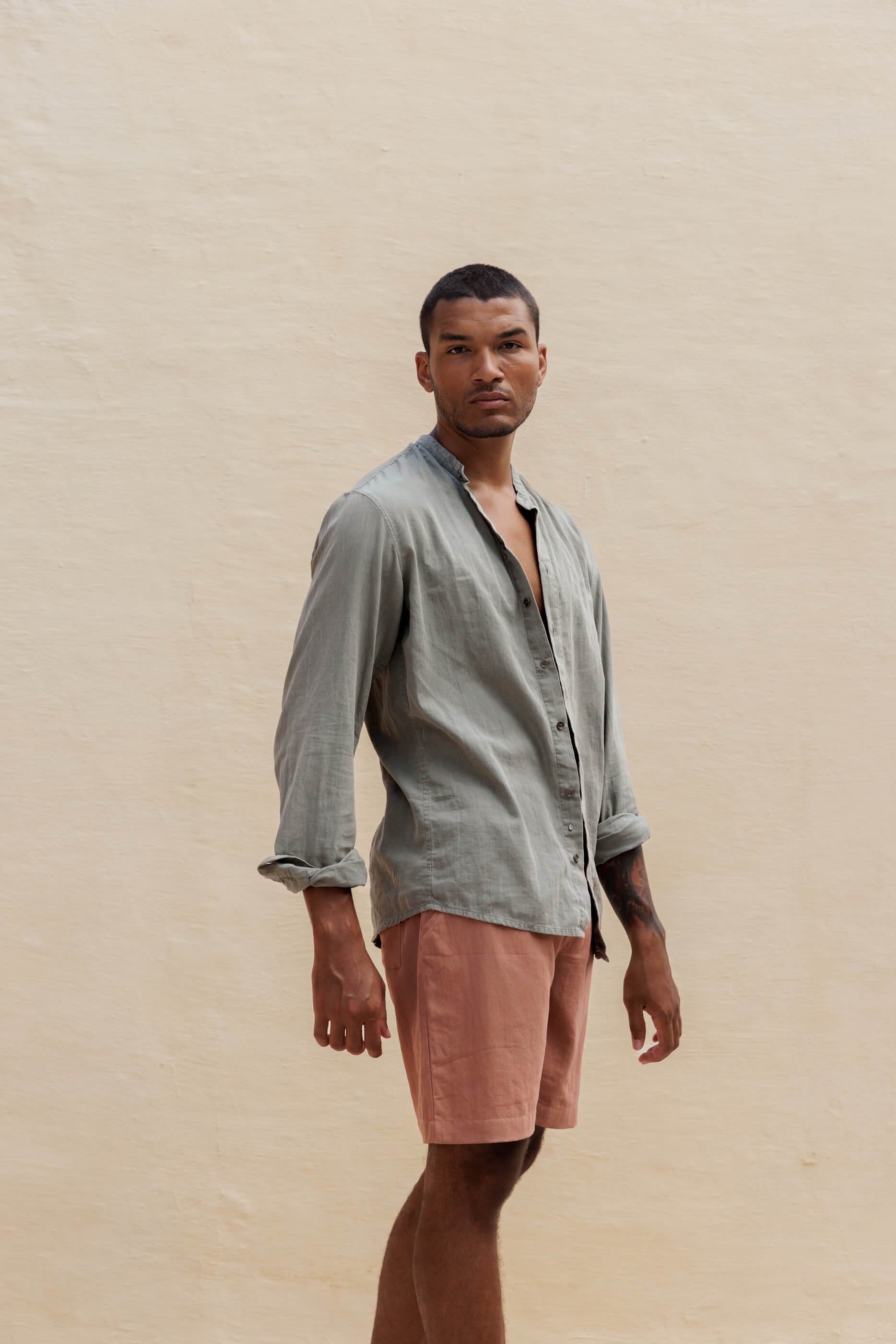 Three-quarter front view of the model wearing the Sage Stone Jordi shirt paired with the matching extra-fine cotton Renclì shorts in terracotta Terra Stone for a contrasting lifestyle outfit.