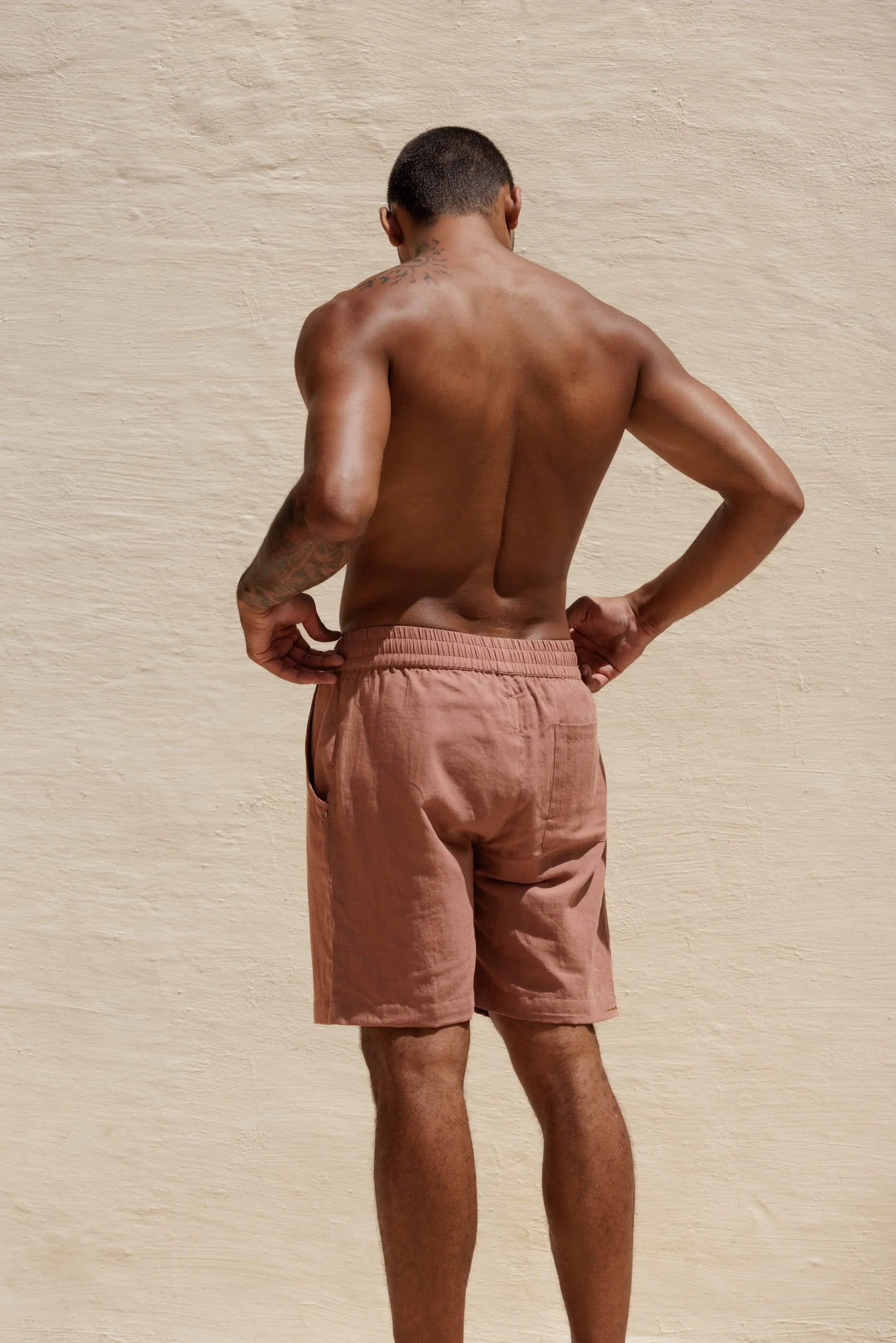 Rear view of the model wearing the Renclì extra-fine cotton shorts in Terra Stone, showcasing the relaxed fit, clean back drape, and the rich terracotta tone.