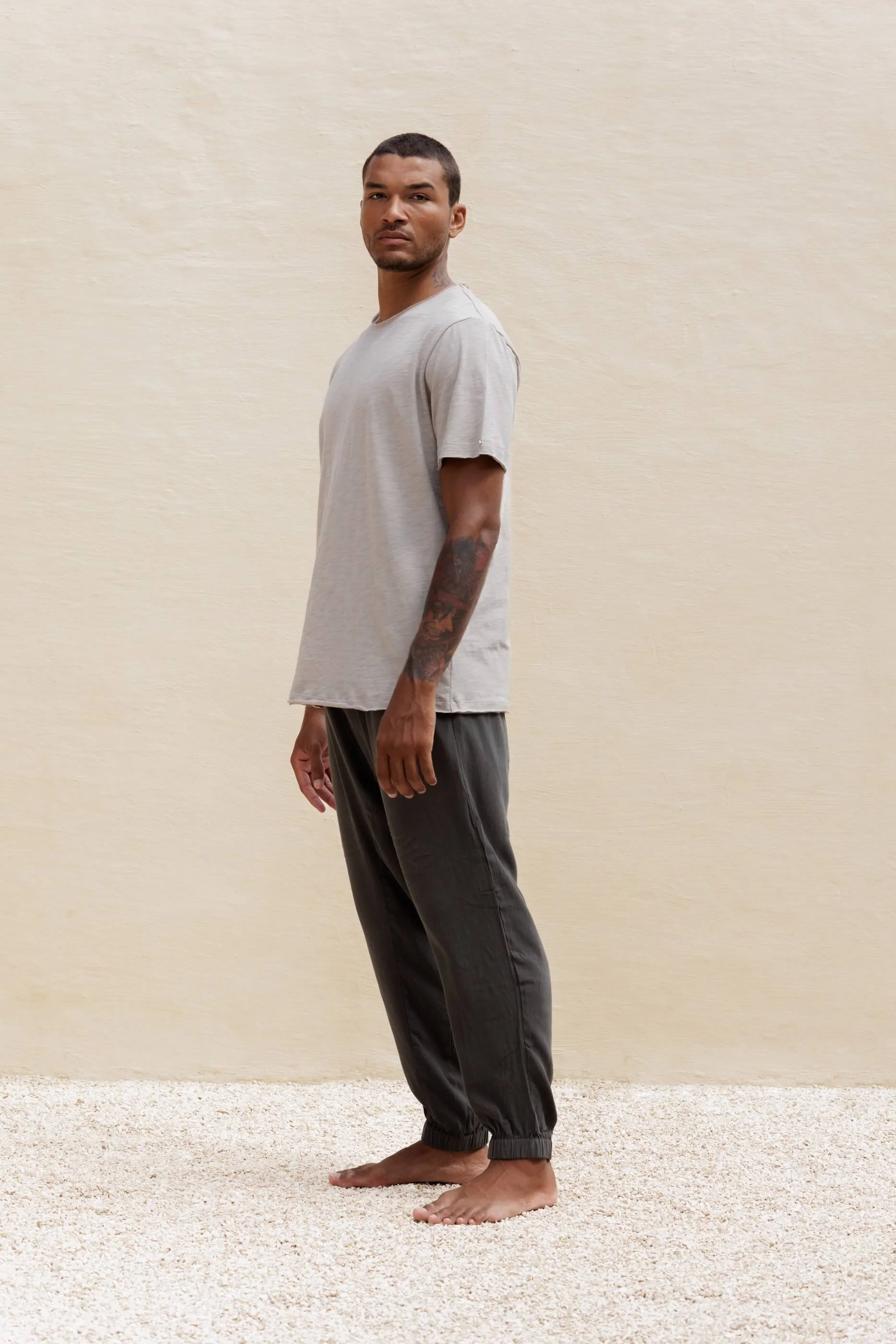 Side profile view of the Nestor T-shirt outfit in Sahara, highlighting the raw-cut double edges at the sleeves and hem with the grey-blue trousers.