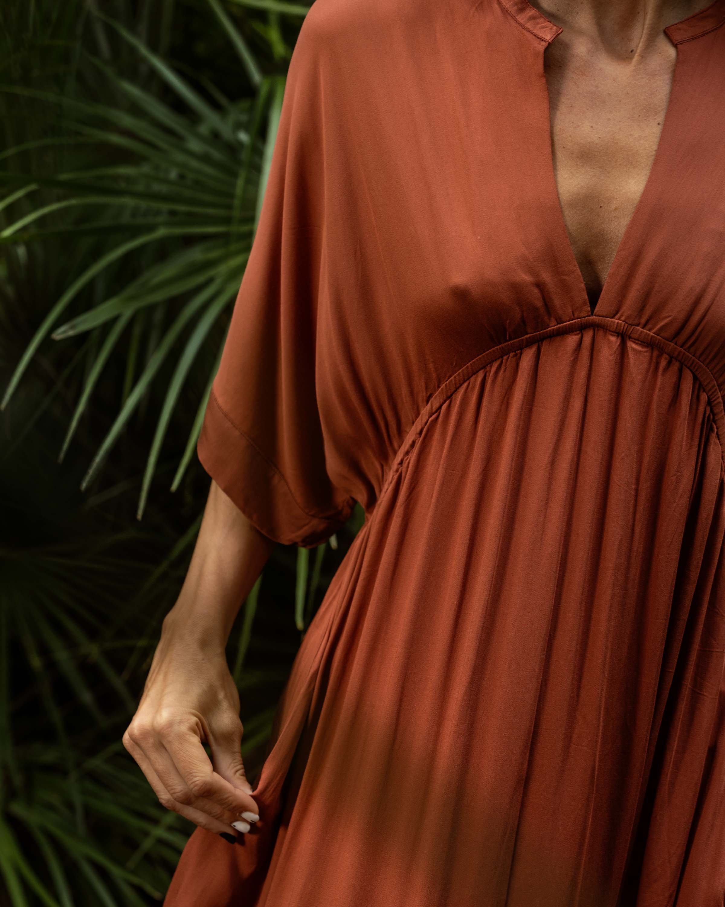 Model wearing Moni Kaftan in Rust Berry, highlighting the elegant silhouette, wide sleeves, and practical side slit for added comfort.