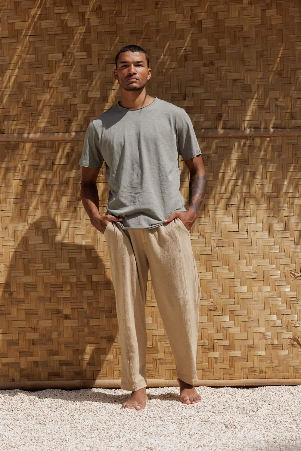 Full-length view of a model pairing the Nestor Dust Grey-green cotton T-shirt with elegant beige trousers, showcasing a refined leisurewear outfit.