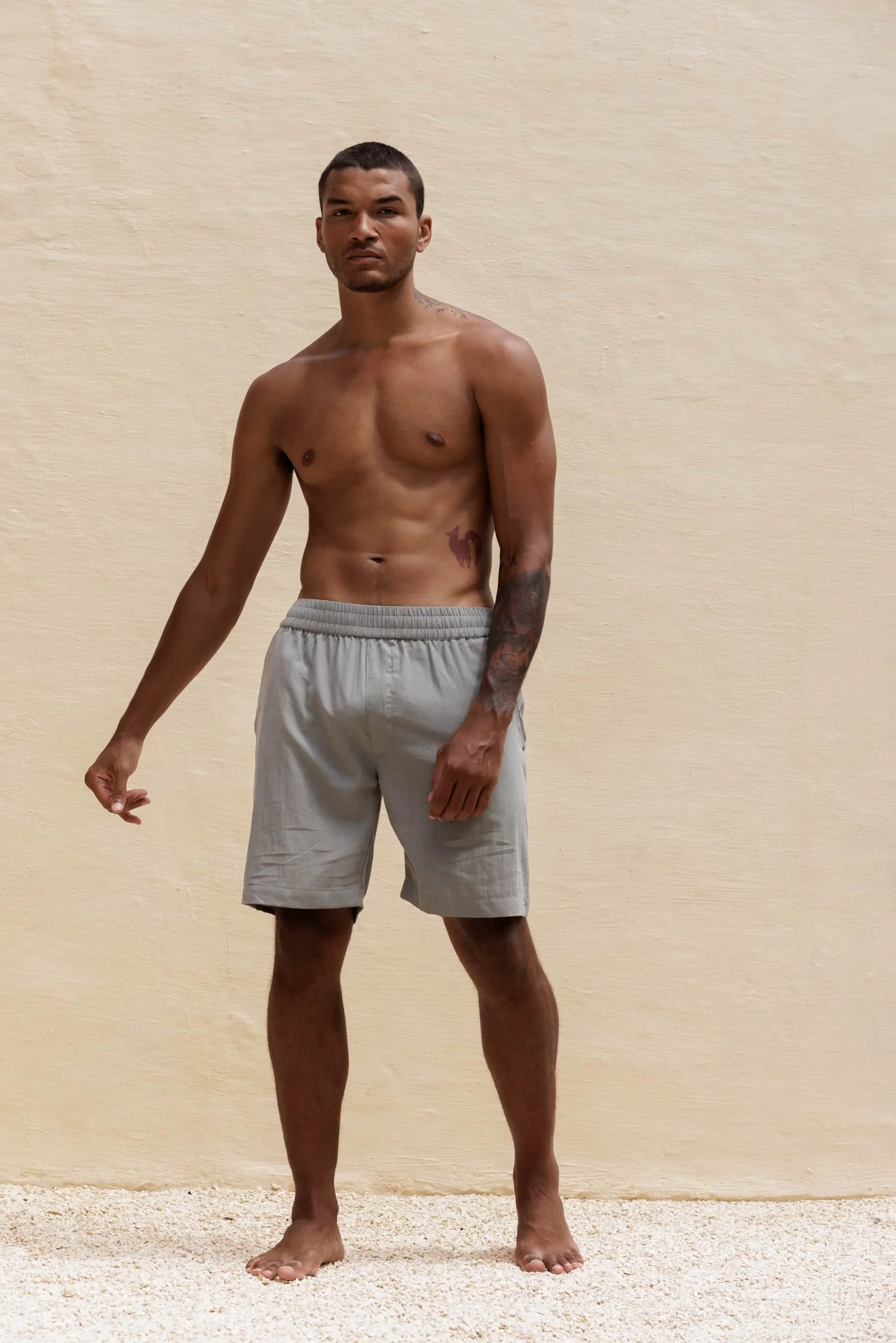 Full-length front view of the model wearing the Renclì extra-fine cotton shorts in Sage Stone, showcasing the relaxed fit, sporty cut, and soft stonewashed grey-green texture.