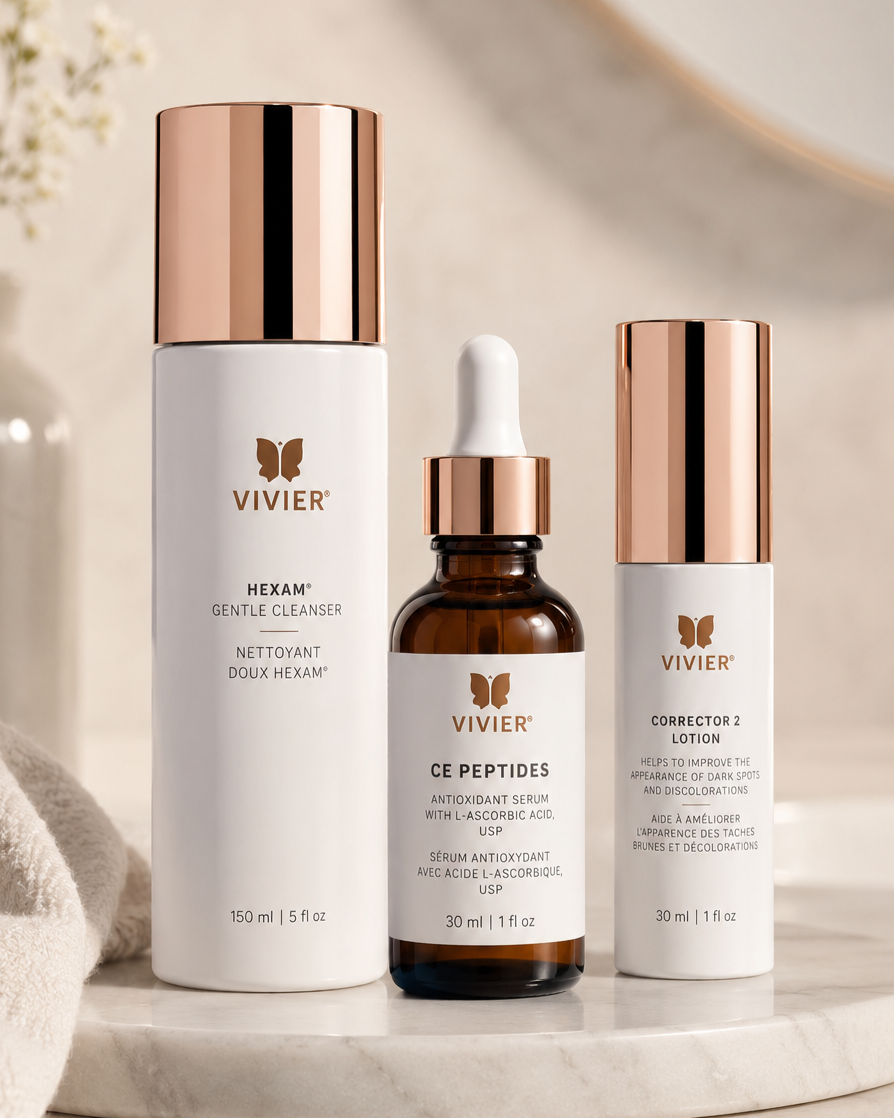 Skincare products from Vivier, including a gentle cleanser, antioxidant serum with L-ascorbic acid, and dark spot corrector, arranged on a marble surface.