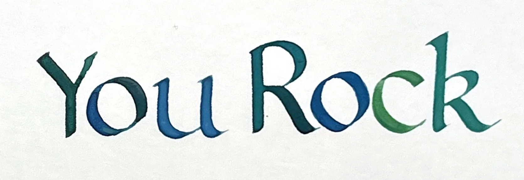 Little Art House Foundation Hadley Park Library Class Broad Edge Calligraphy — The words "You Rock" handwritten in colorful teal, blue, and green broad-edge calligraphy on white paper.