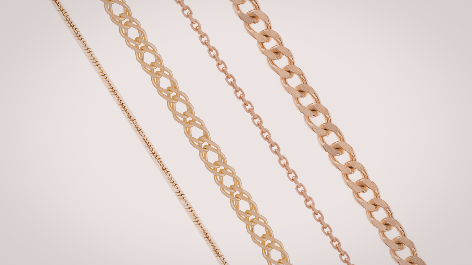 Four different styles of gold chains hanging diagonally against a plain background.