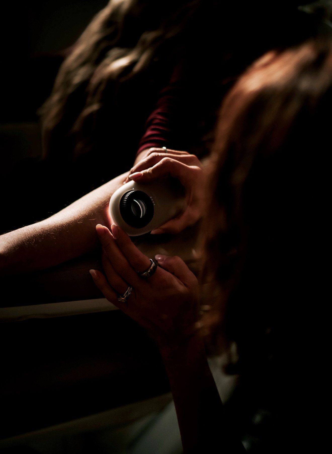 Person holding a flashlight with both hands in a dark setting, with long hair partially visible.