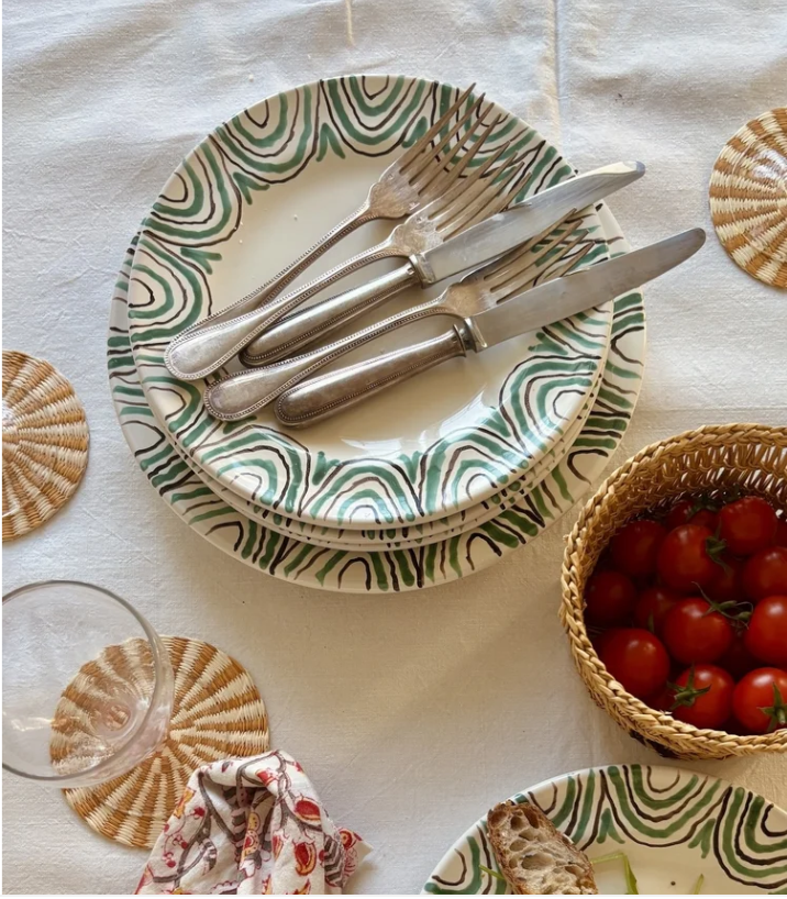 3 fourchettes et 2 couteaux posés sur des assiettes à motifs verts