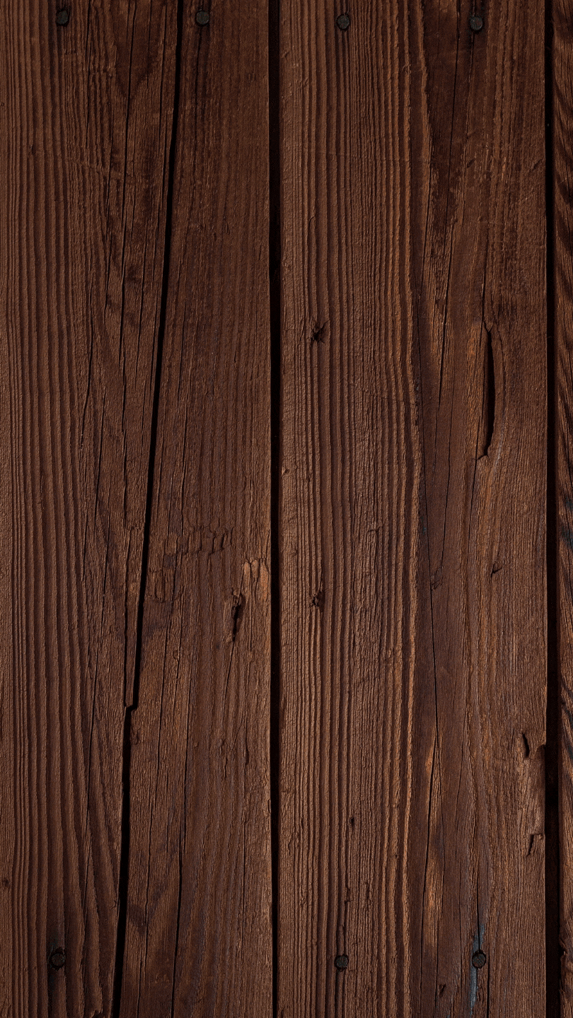 Close-up of a wooden surface with visible grain, knots, and nail heads.