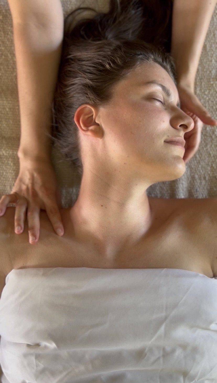 A person receiving a massage or acupuncture on their back from a practitioner in a dimly lit room.