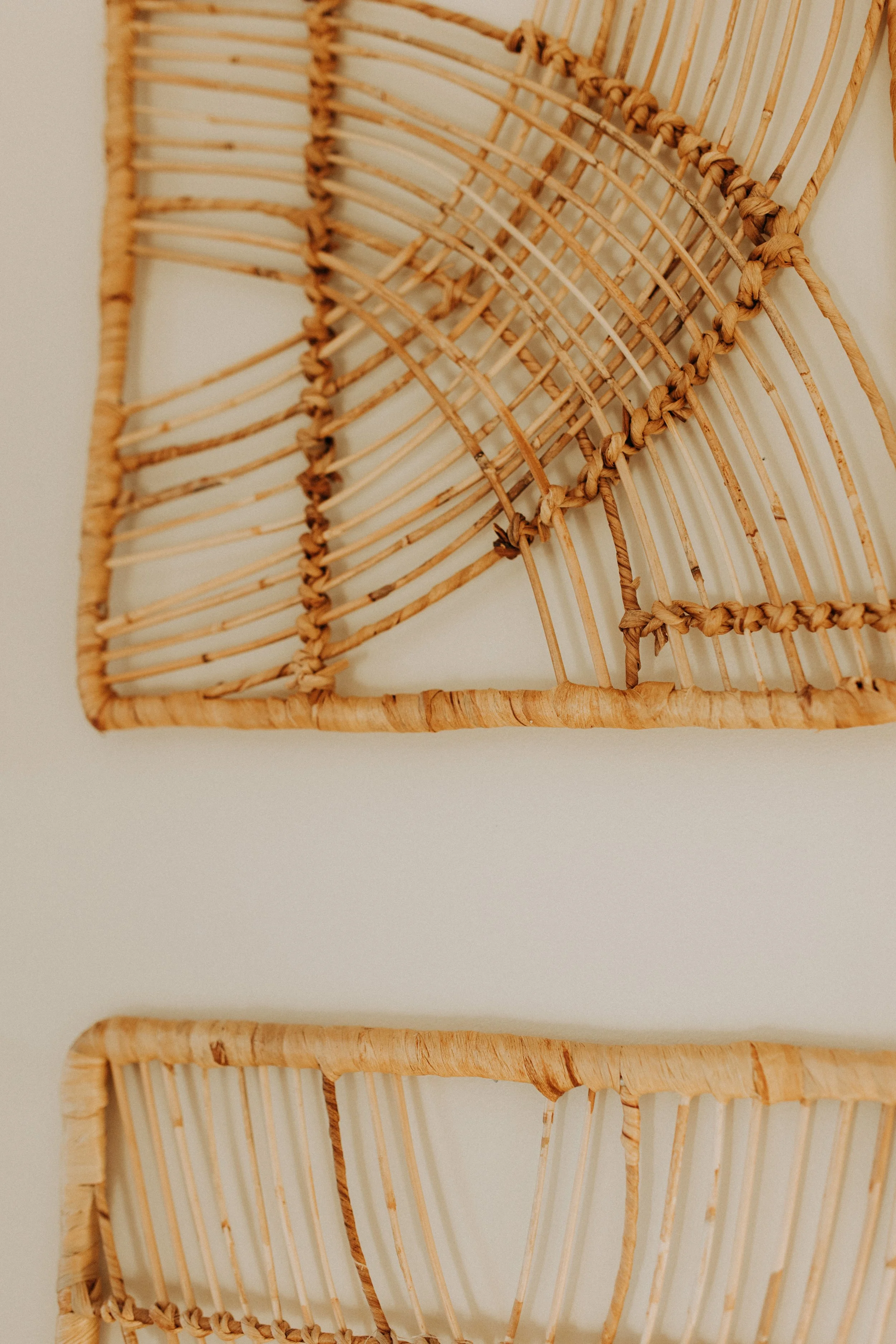 Close-up of woven rattan or wicker shelves mounted on a white wall.