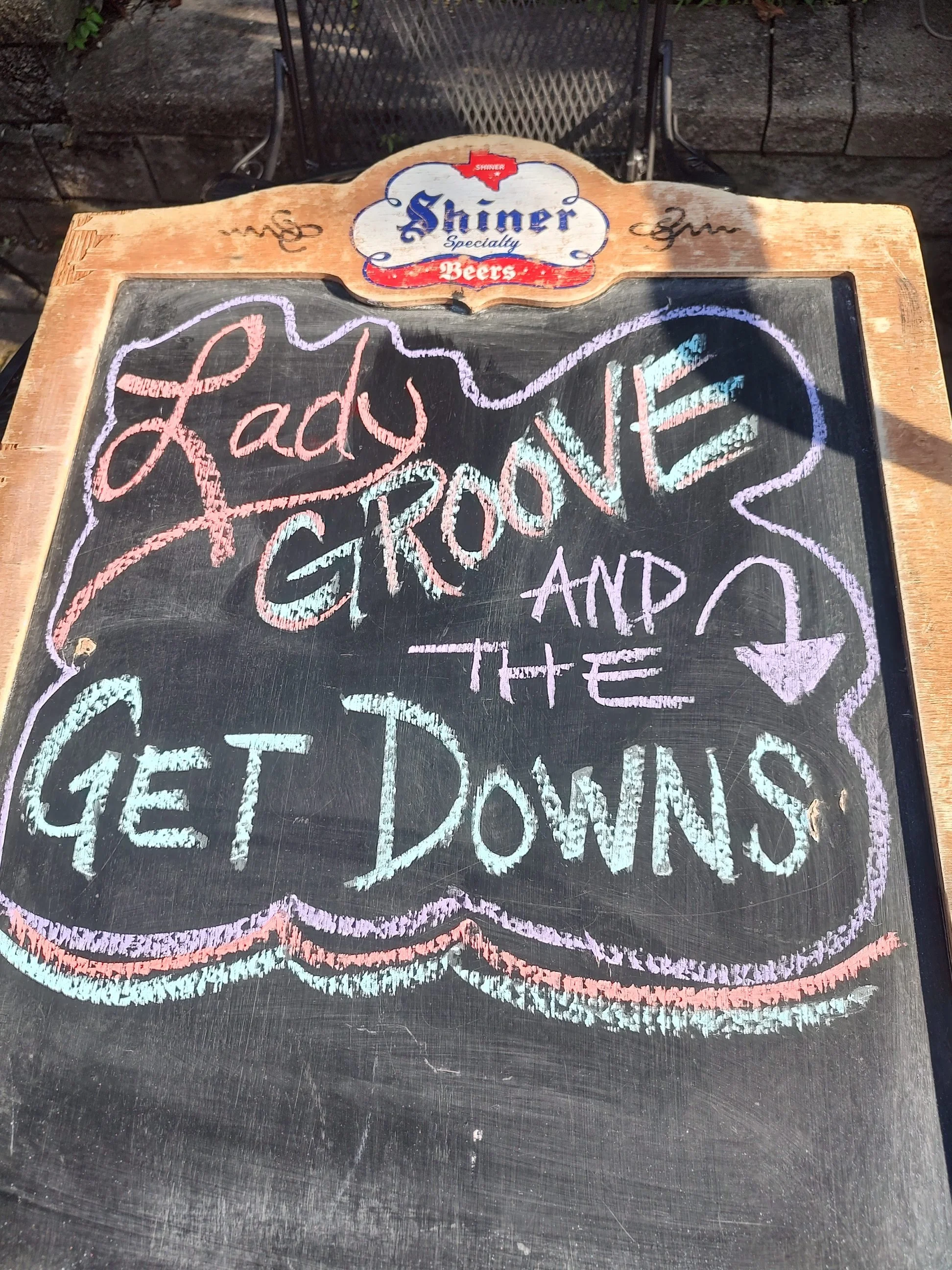 Chalkboard with "Lady Groove and the Get Downs" written in colorful chalk, with "Shiner Specialty Beers" logo at the top.