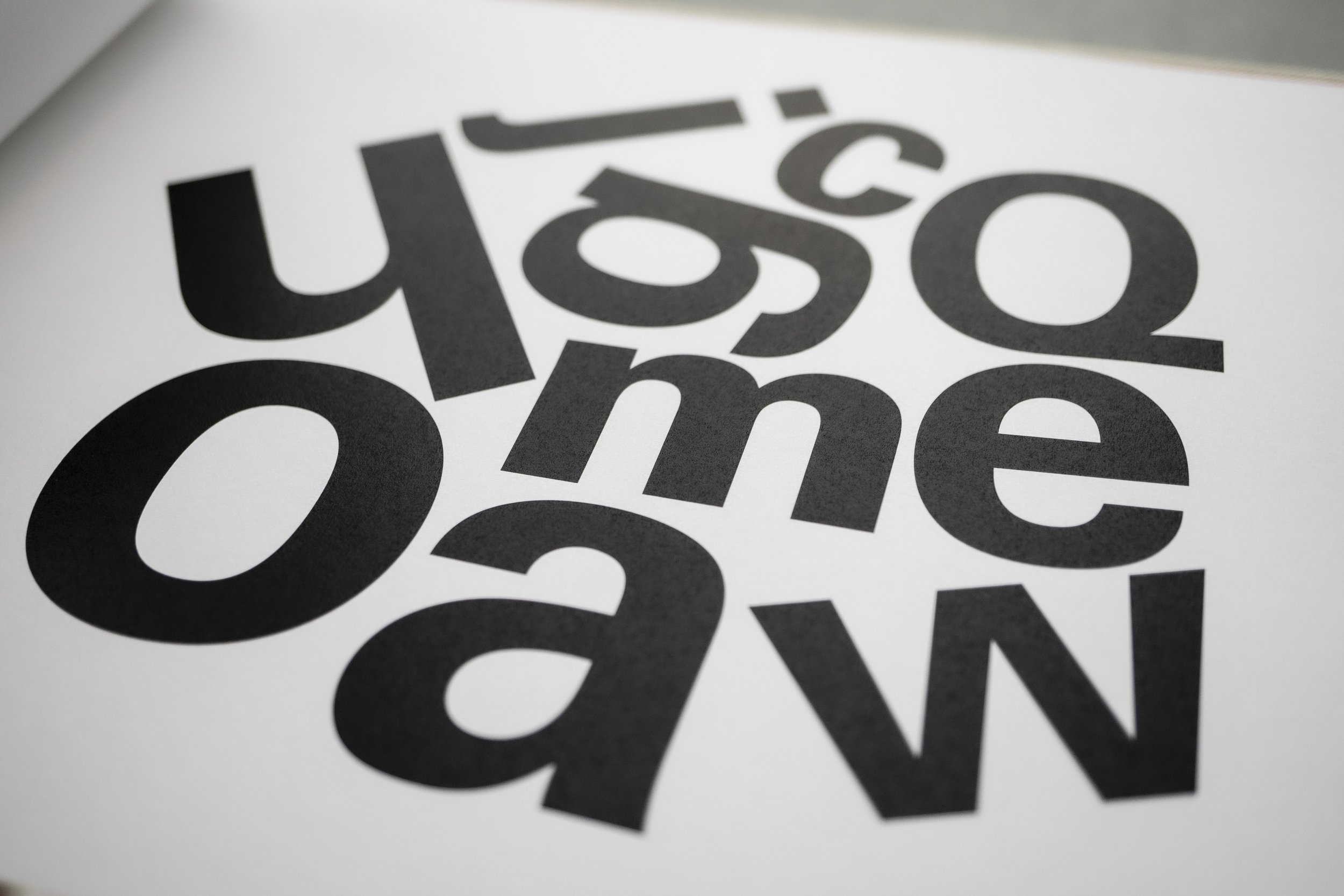 Large jumbled letters on a page printed in black ink to celebrate the Frutiger typeface designed by Adrian Frutiger in 1975.