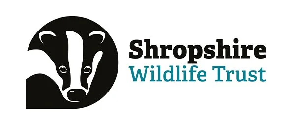 Shropshire Wildlife Trust logo with a stylized badger head in black and white, and the organization name in black and blue text.