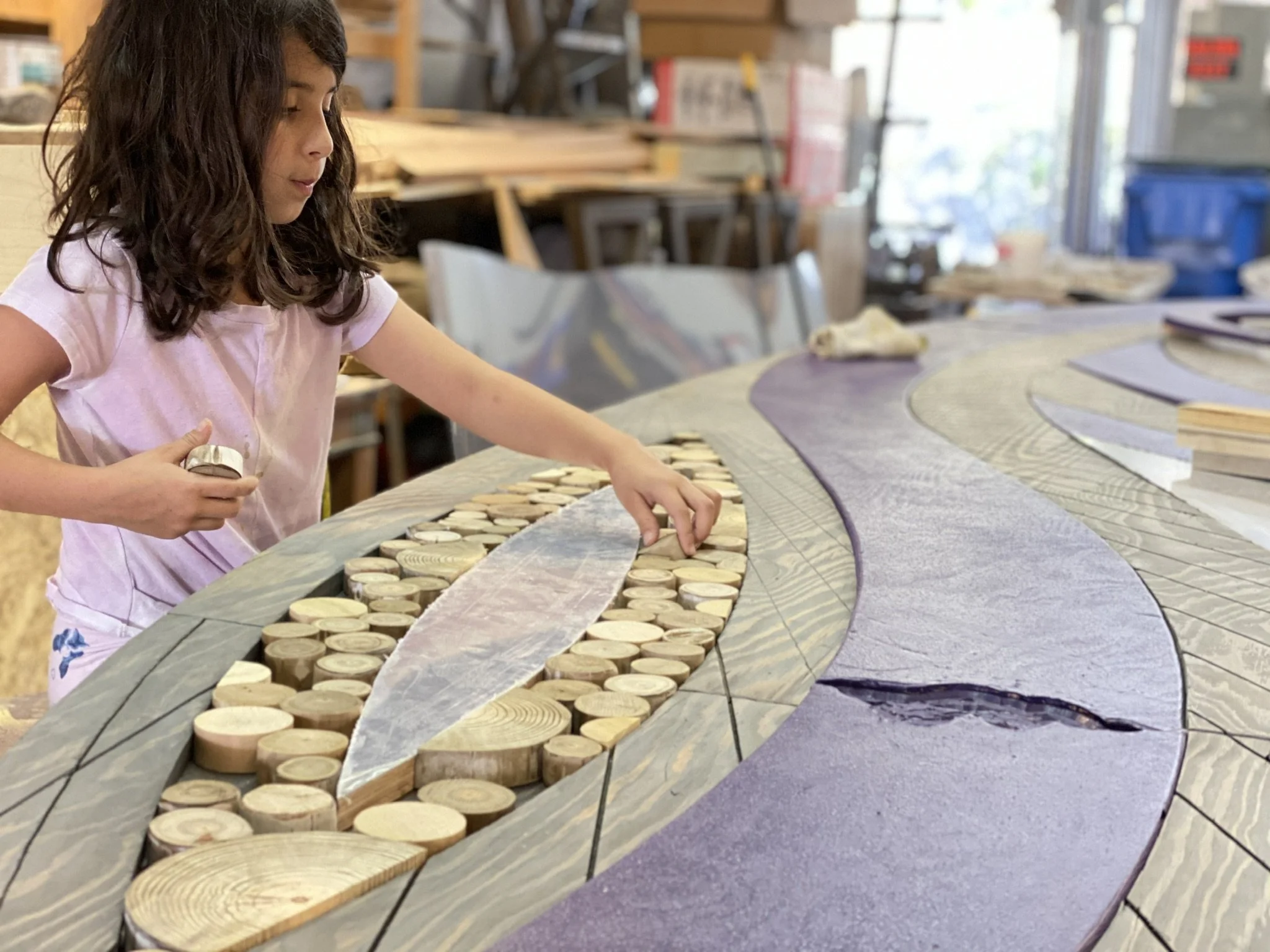 Young girl in a purple shirt helps to assemble a custom wood wall art. 