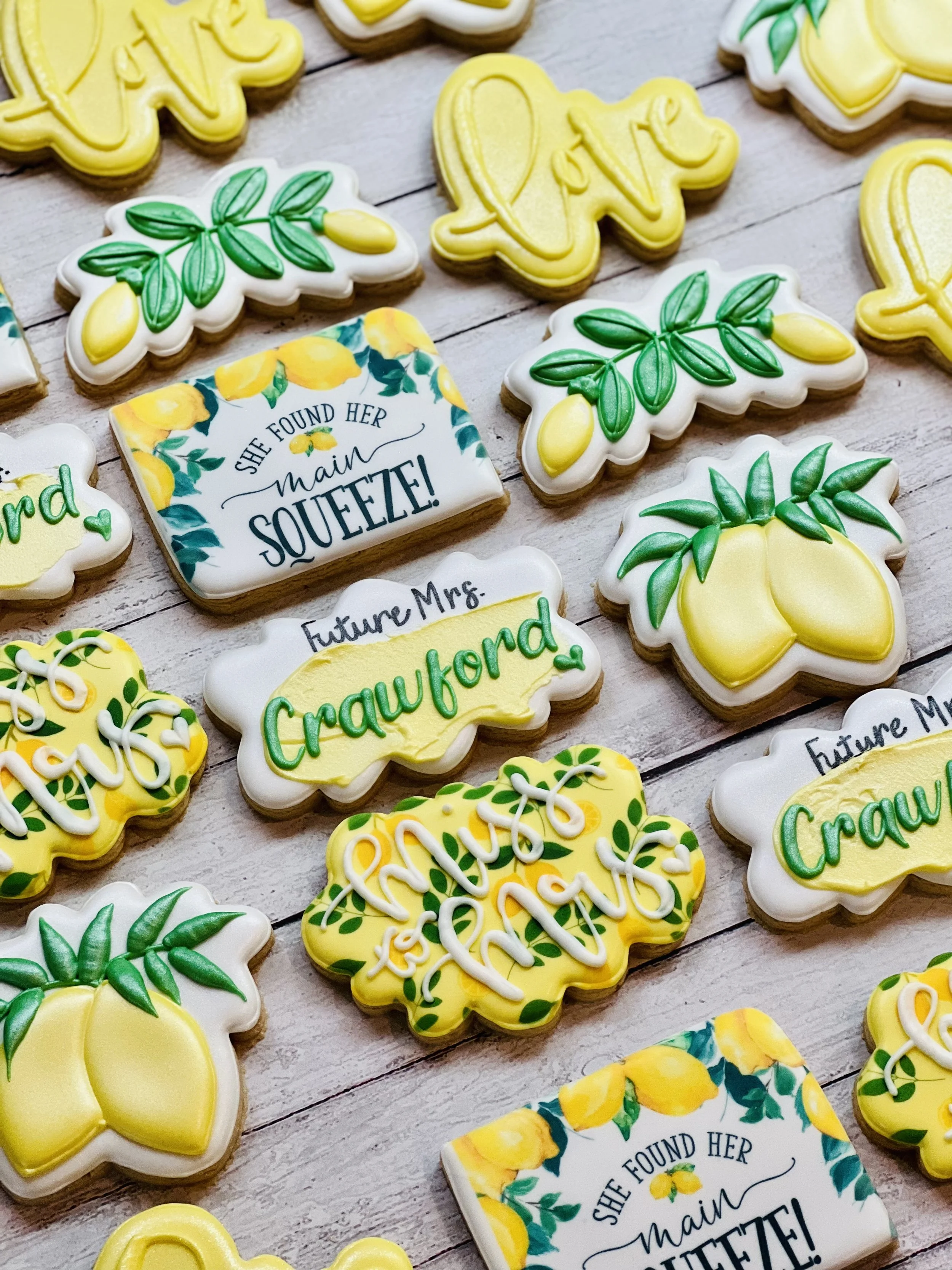 Decorated cookies with lemon and leaf designs, featuring phrases like "Future Mrs.," "Miss to Mrs.," and "She found her main squeeze." Cookies are in yellow, green, and white.