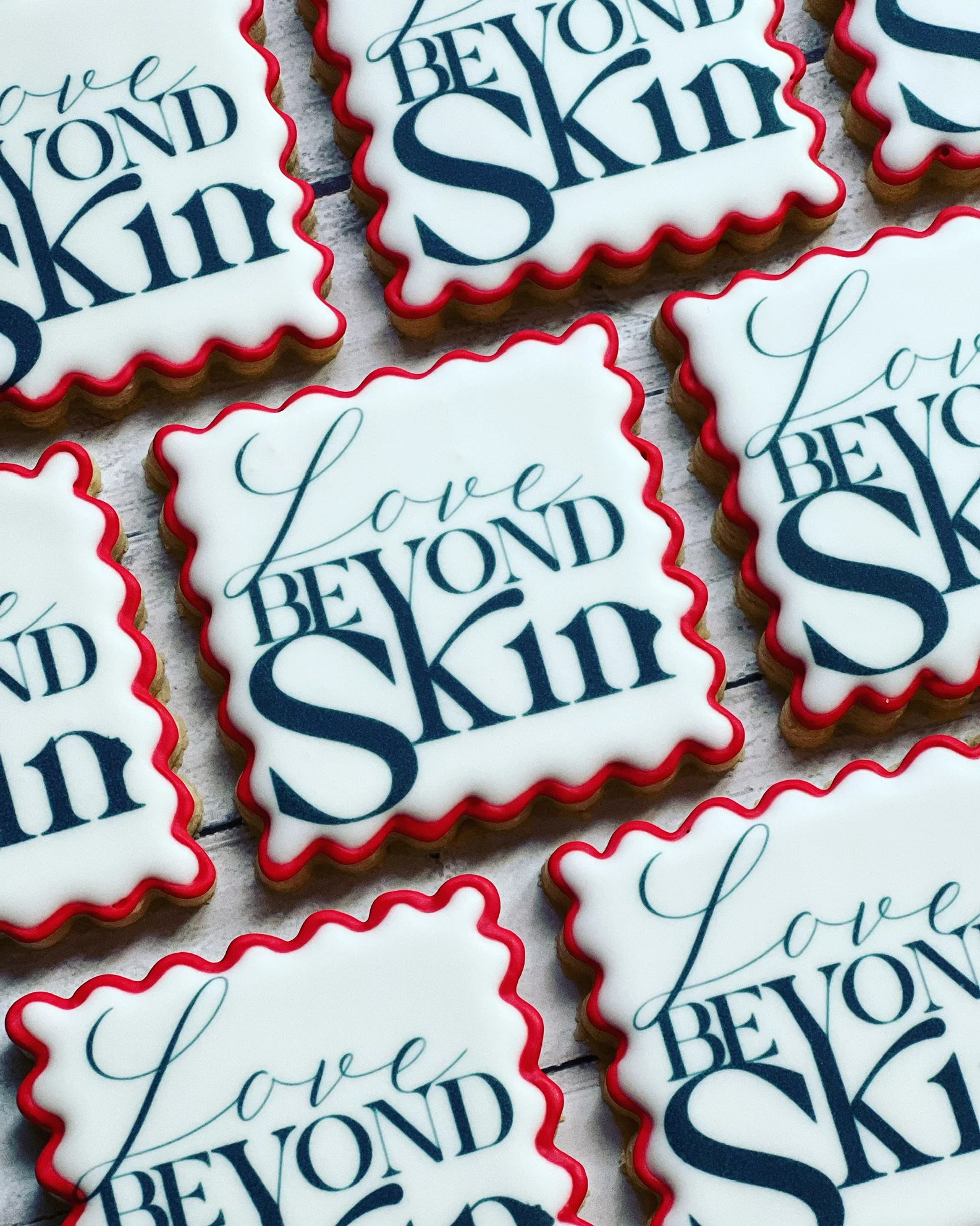 Square cookies with white icing and red edges, featuring the text "Love Beyond Skin."