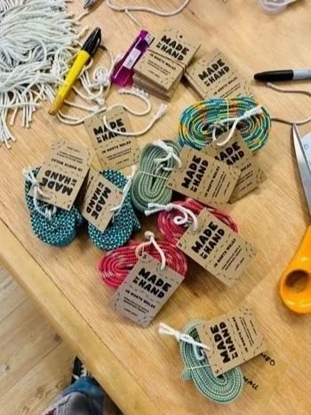 a selection of colourful belts made of dynamic climbing rope lay on the table having been labelled with a sharpie and twine, both visible on the table