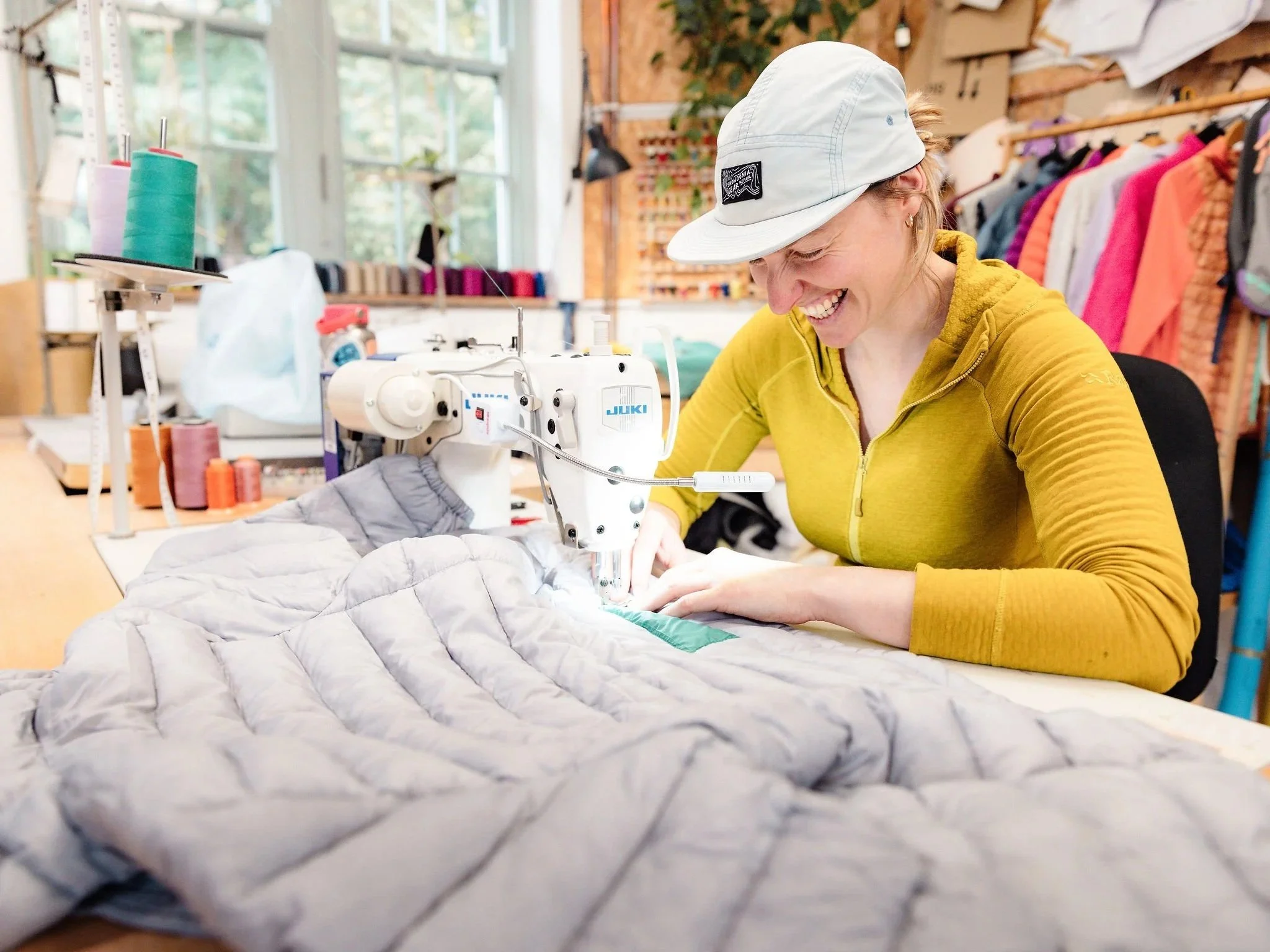 Woman smiling while stitching a sewn patch on a Rab jacket