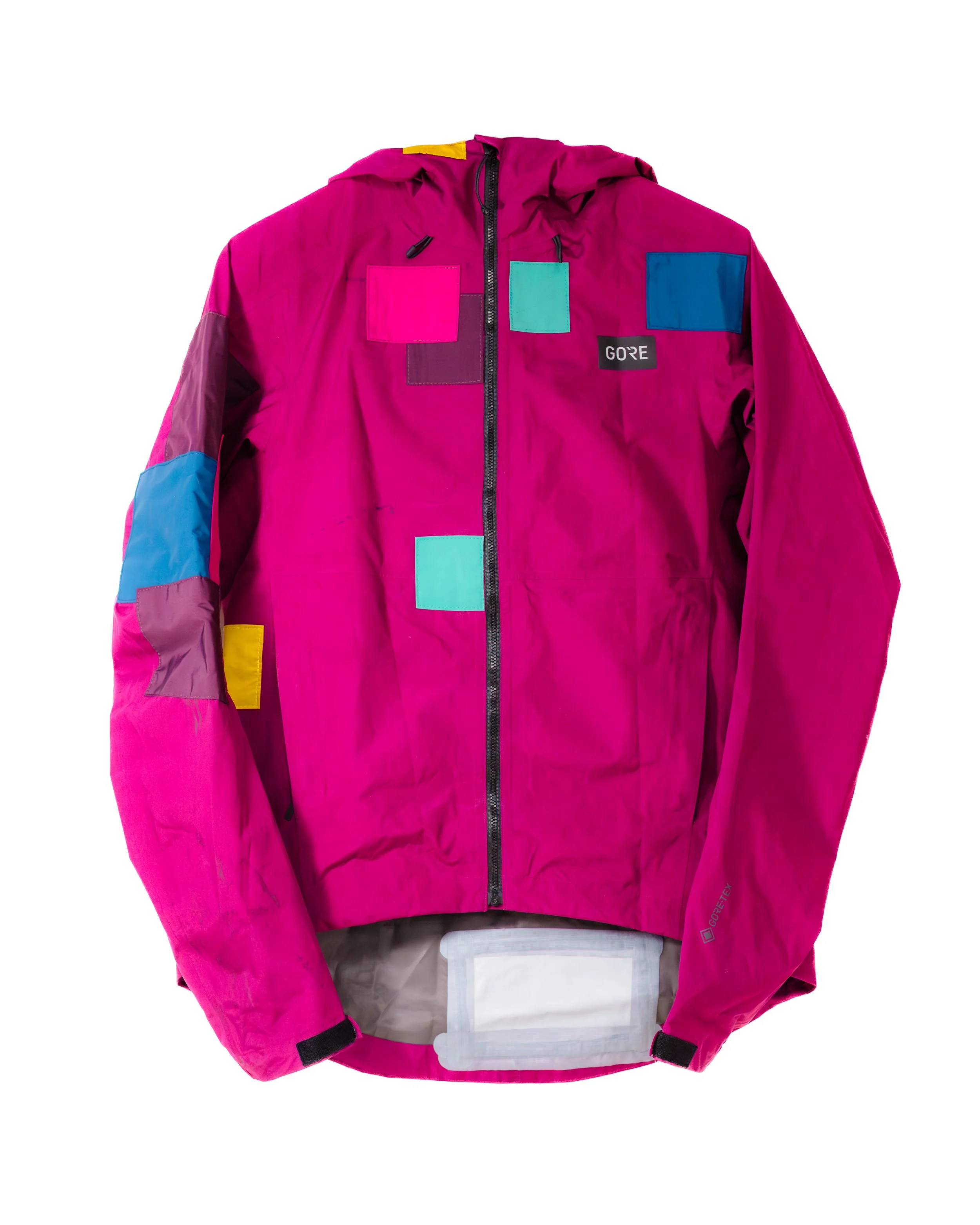 pink waterproof jacket with colourful sewn patches on the body and arms in pink, turquoise, blue, purple, and yellow.