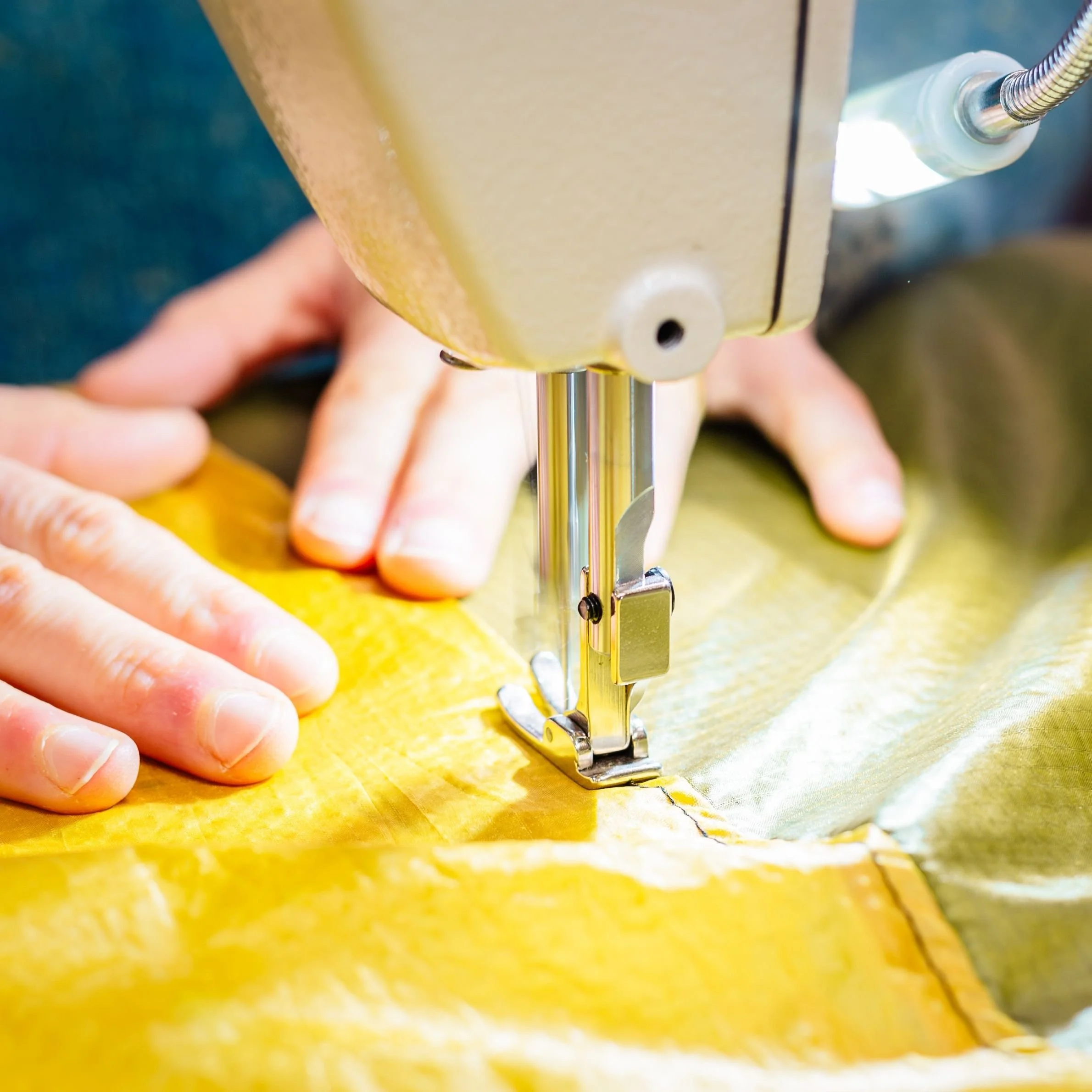 two hands fixing a burst seam on industrial sewing machine