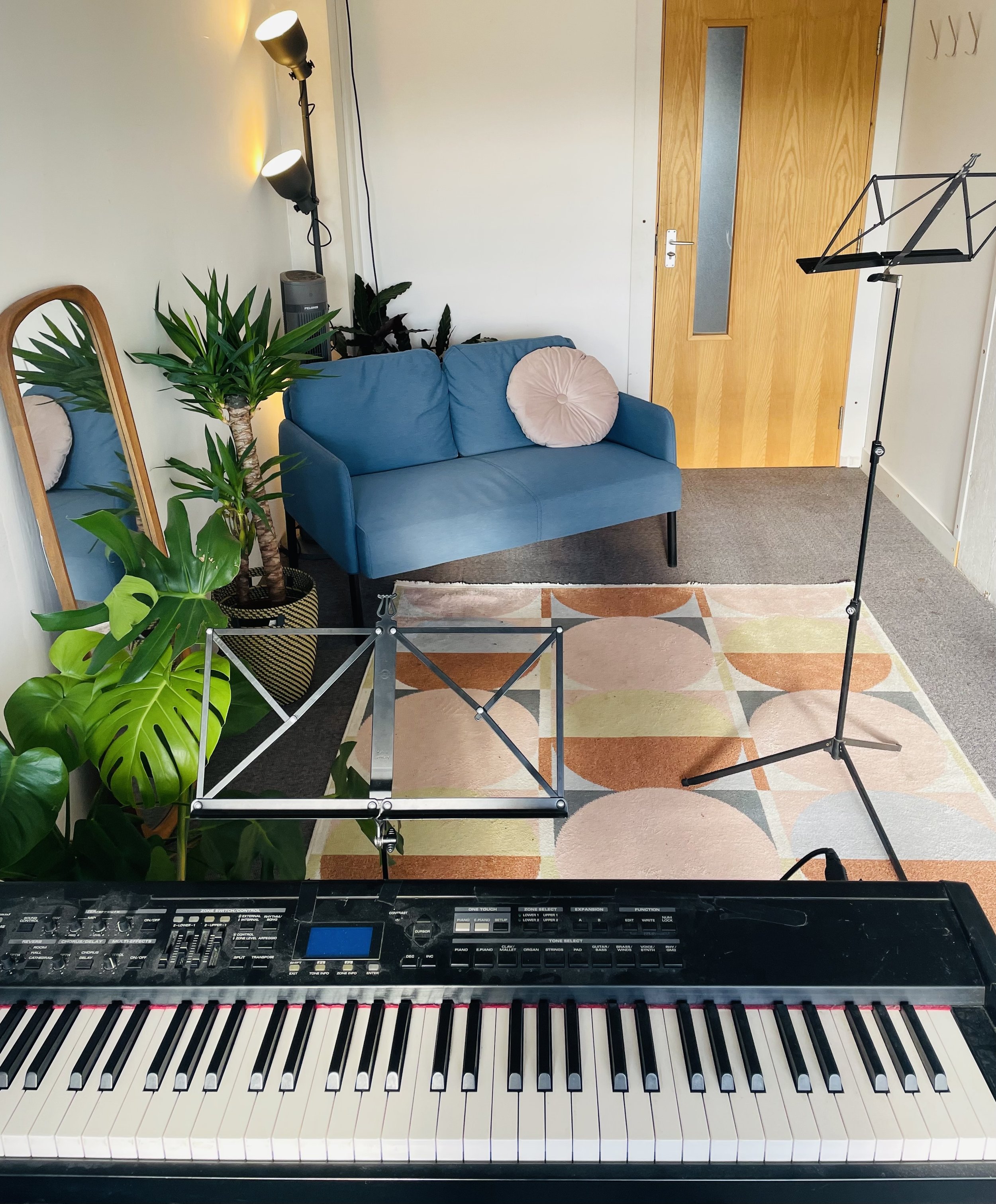 a bright a colourful studio with a piano in the foreground and a music stand