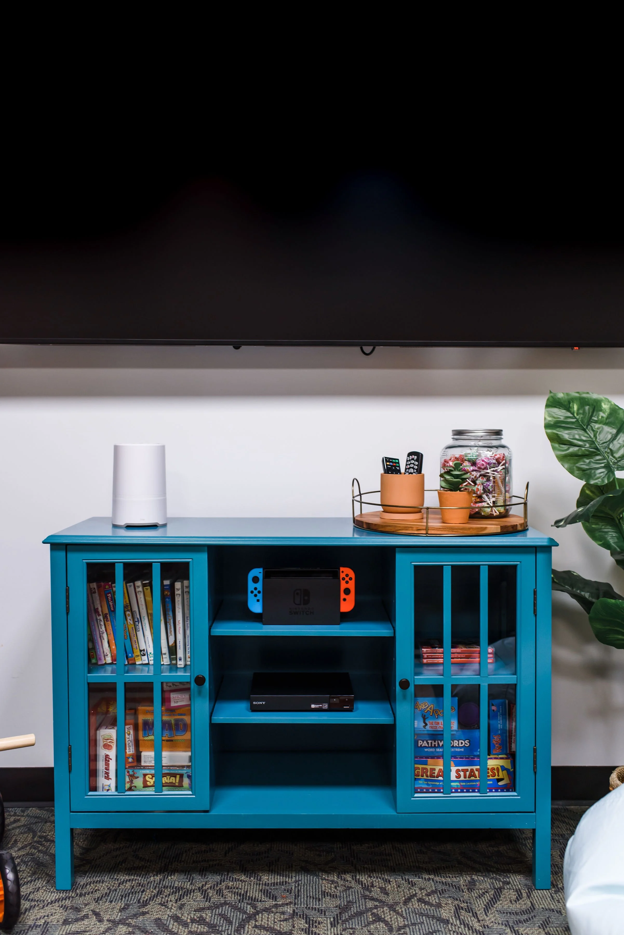 The TV cabinet stores games, DVDs, Nintendo Switch + games and a 3 in 1 air purifier, sound machine and night light. 