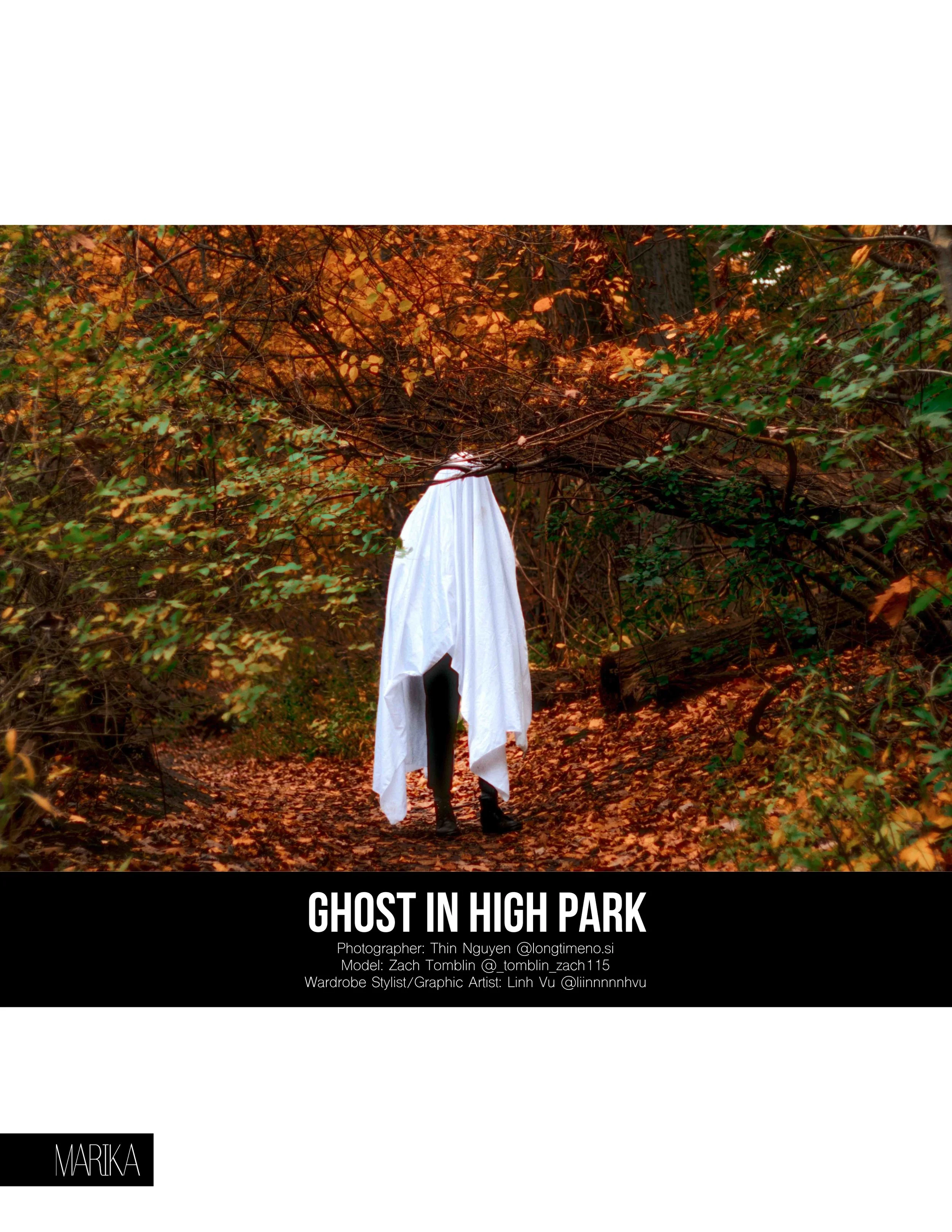 A spooky figure dressed as a ghost with a white sheet and black boots, standing on a wooded path with orange and green autumn leaves.