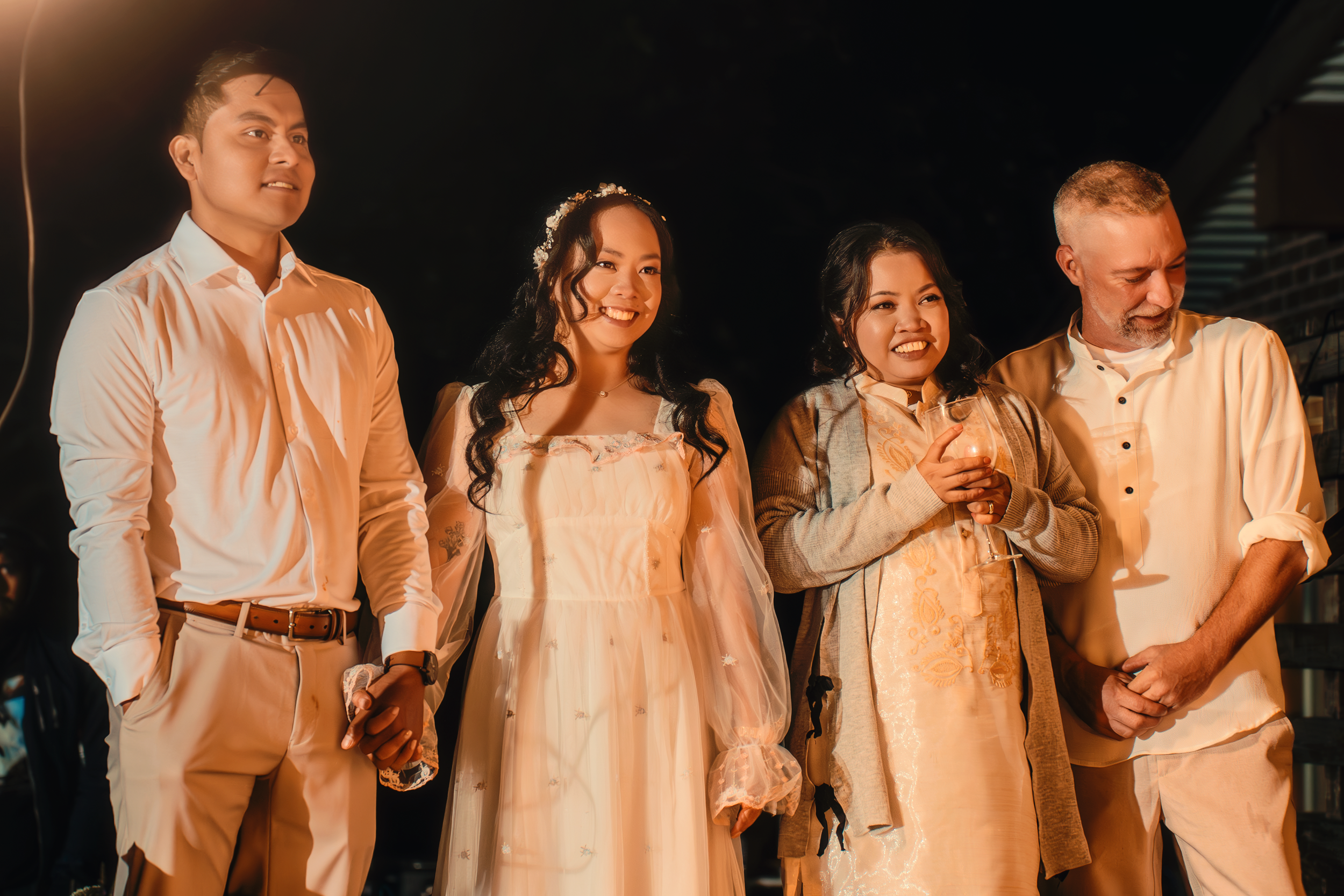 Group of five people standing together indoors at night, two women and three men, at a social event.