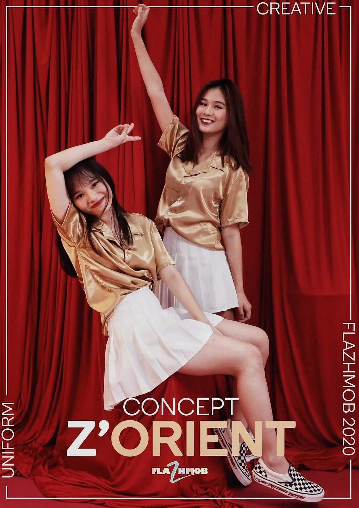 Two young women in gold satin shirts and white pleated skirts posing against a red curtain backdrop, smiling and making playful gestures.