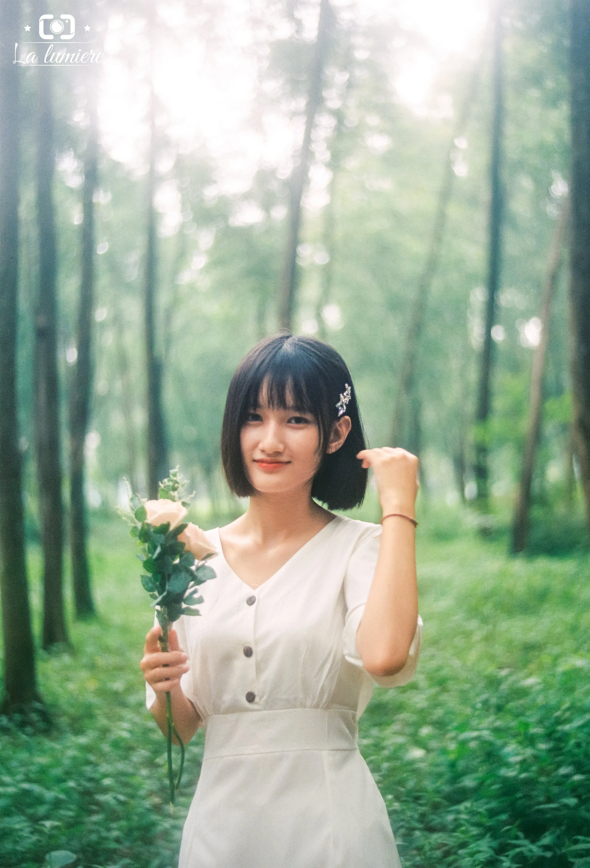 A young woman in a white dress holding a bouquet of roses in a lush green forest.