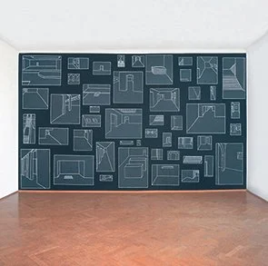 A large chalkboard with sketches of various furniture and interior layouts on a white wall in a room with wooden floor.