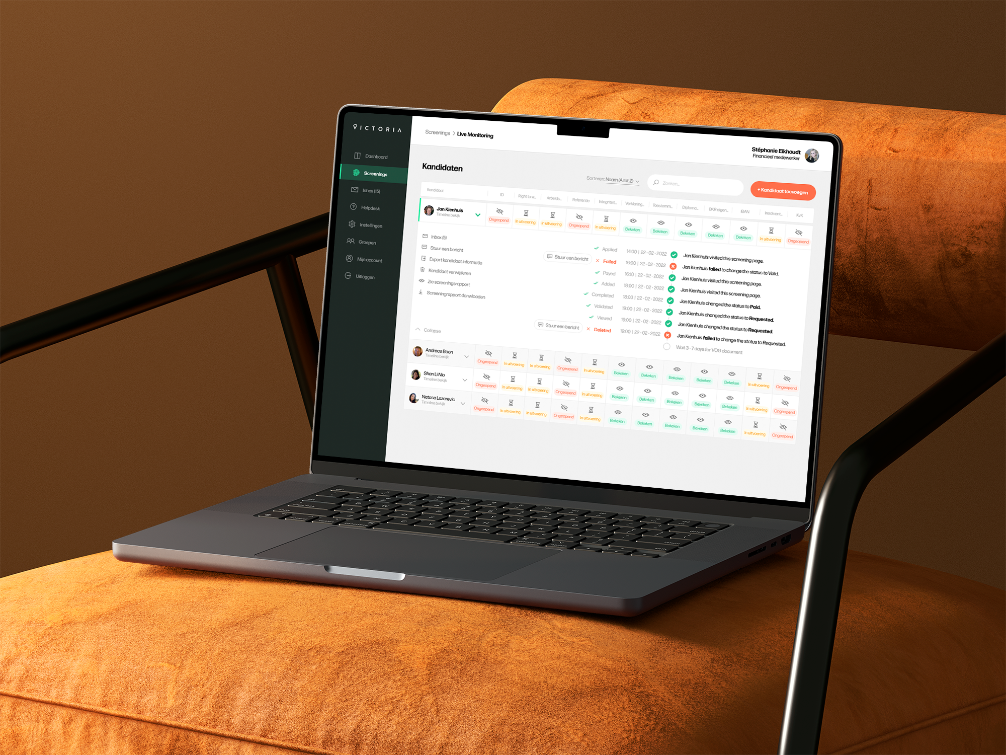Laptop displaying employee screening status on an orange couch.