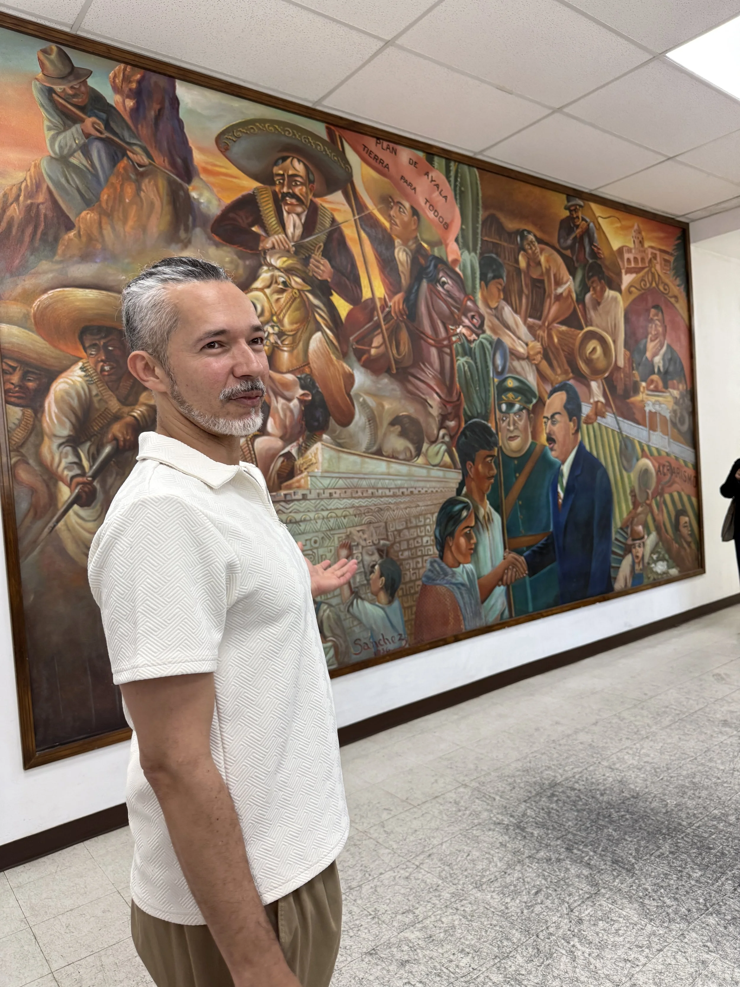 Henry Torres showing an original mural within the facility. (Artist unknown)
