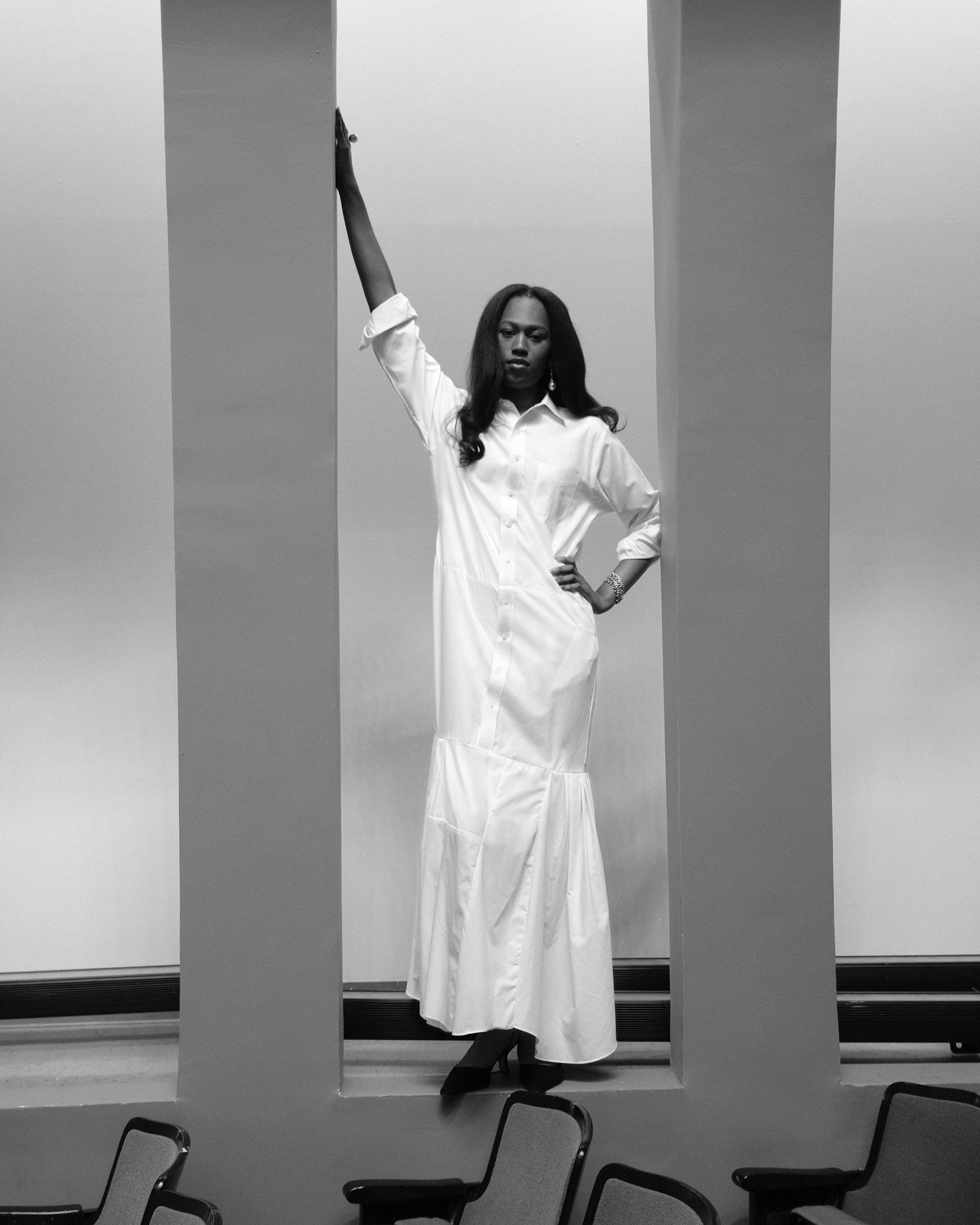 @kai.toussaint.marcel is wearing a shirt-dress made from five Brooks Brothers shirts sewn together. The top is a single shirt with the torso of another attached below to extend the length. The flounce panel is constructed from three additional shirts