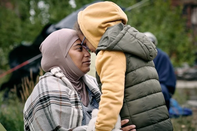 Woman and child outside gently pressing foreheads together