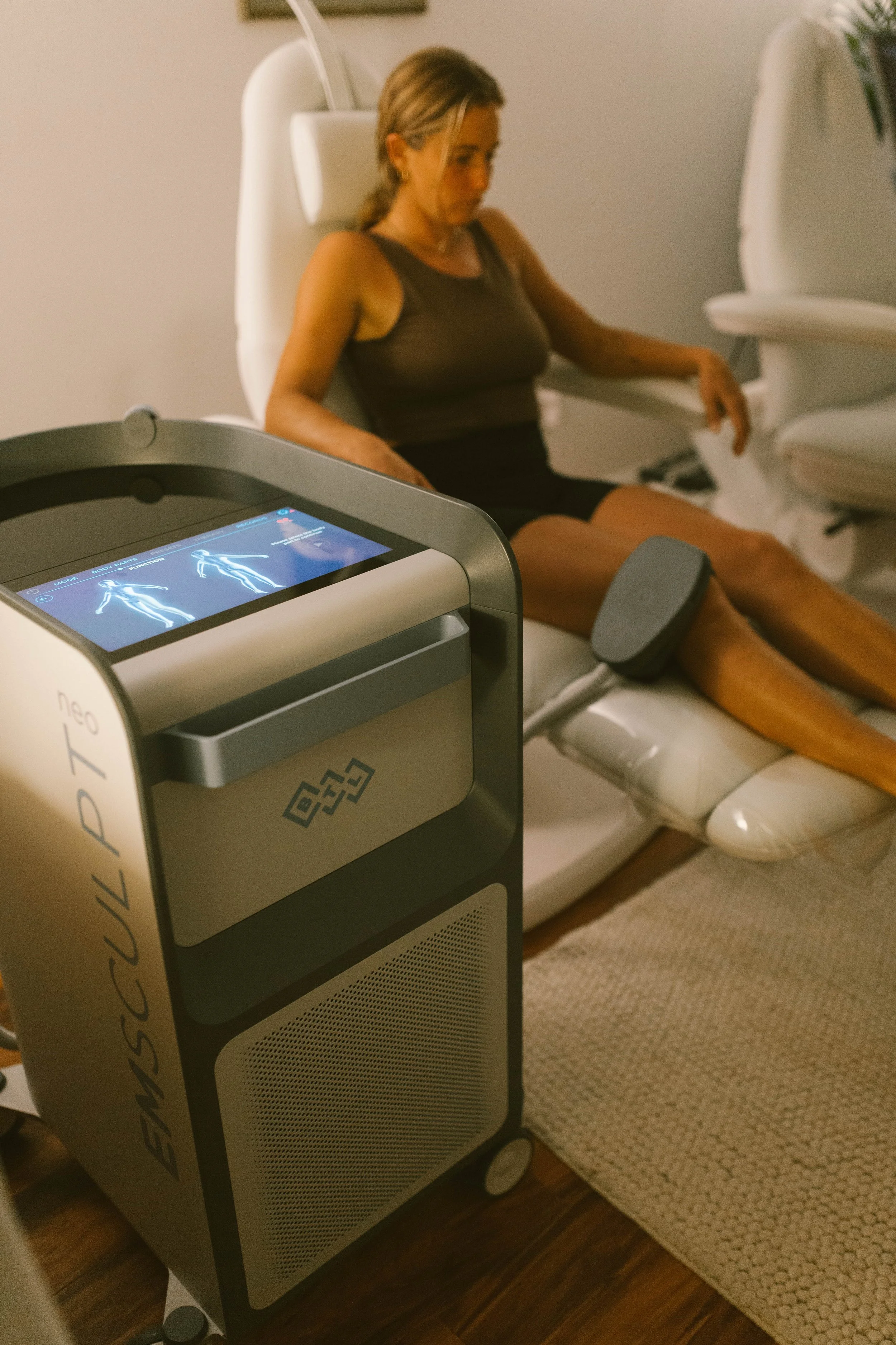A woman receiving a treatment on her legs with a laser device in a spa or medical clinic.