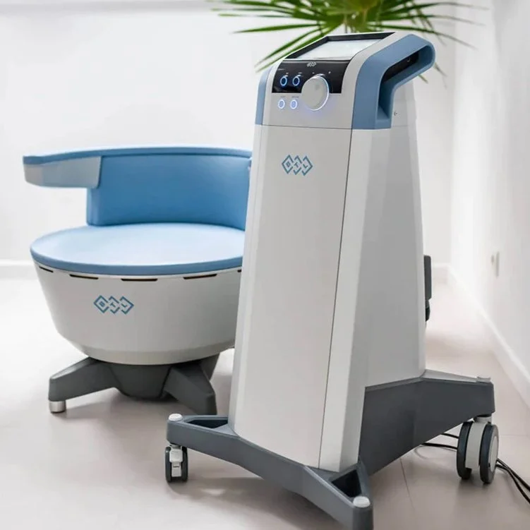 A medical device and chair in a clinical setting, with a plant in the background.