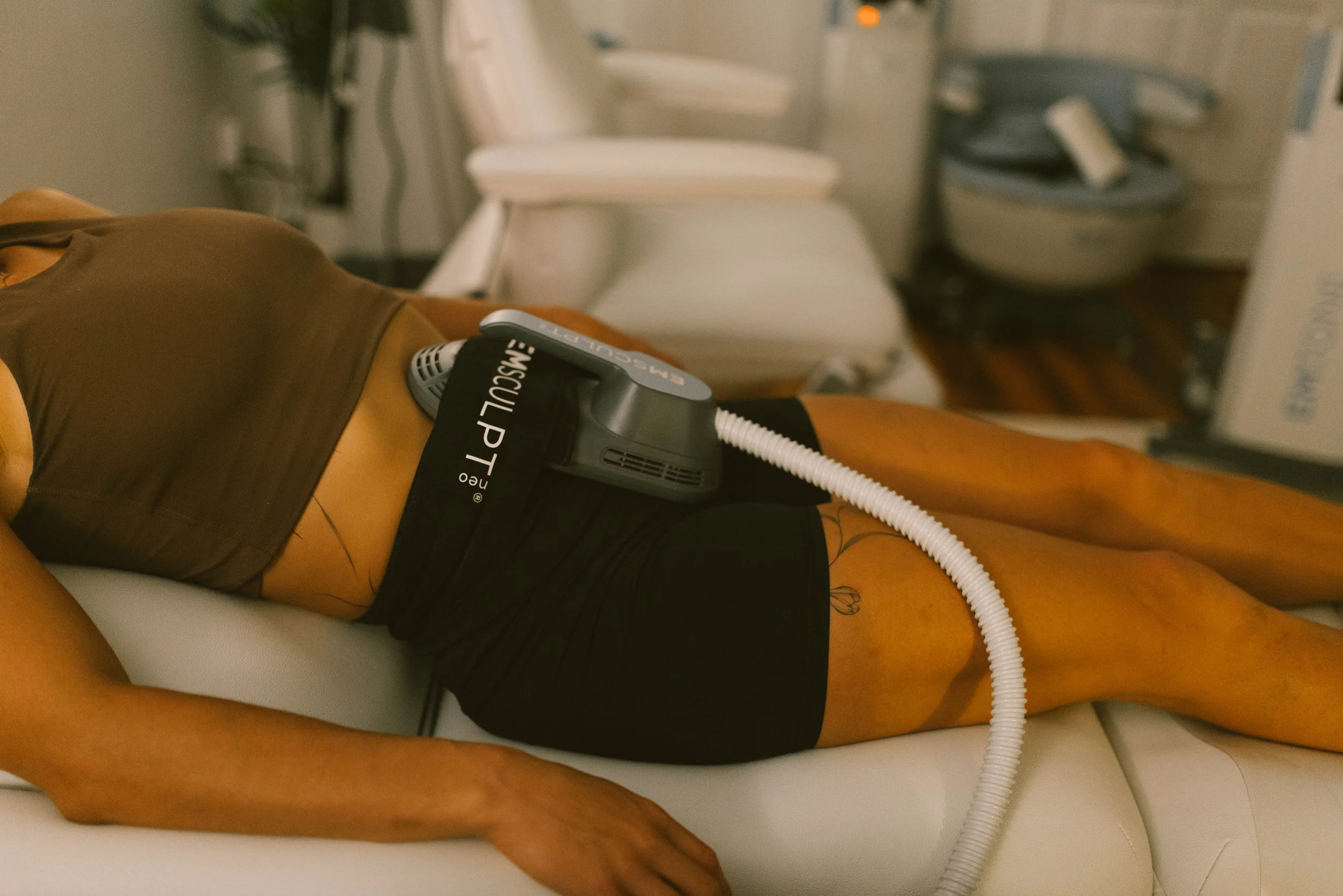 A person lying on a hospital bed receiving a medical procedure with a respiratory device attached to their abdomen.
