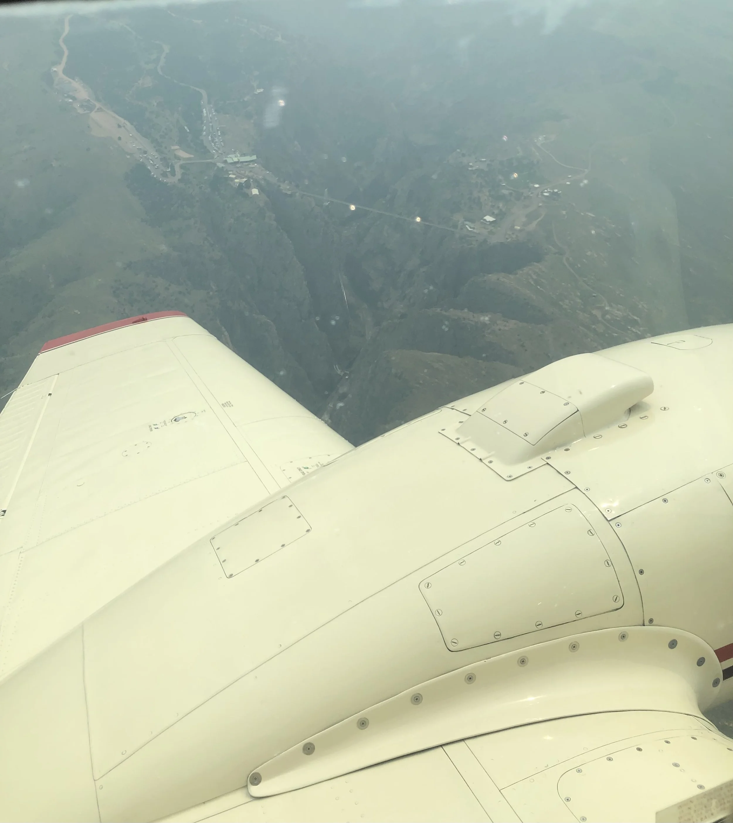 Wing view of a WETSU Aviation Baron D55 over Colorado mountains with less than clear visibility