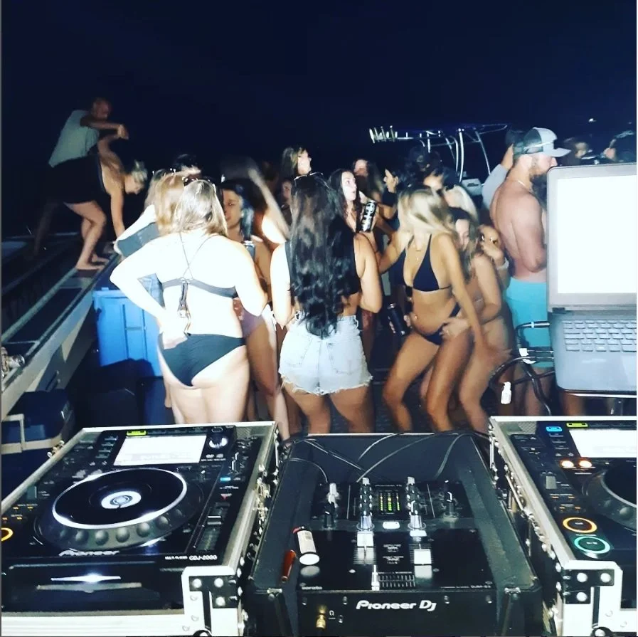 People dancing at a nighttime beach party with DJ equipment in the foreground.