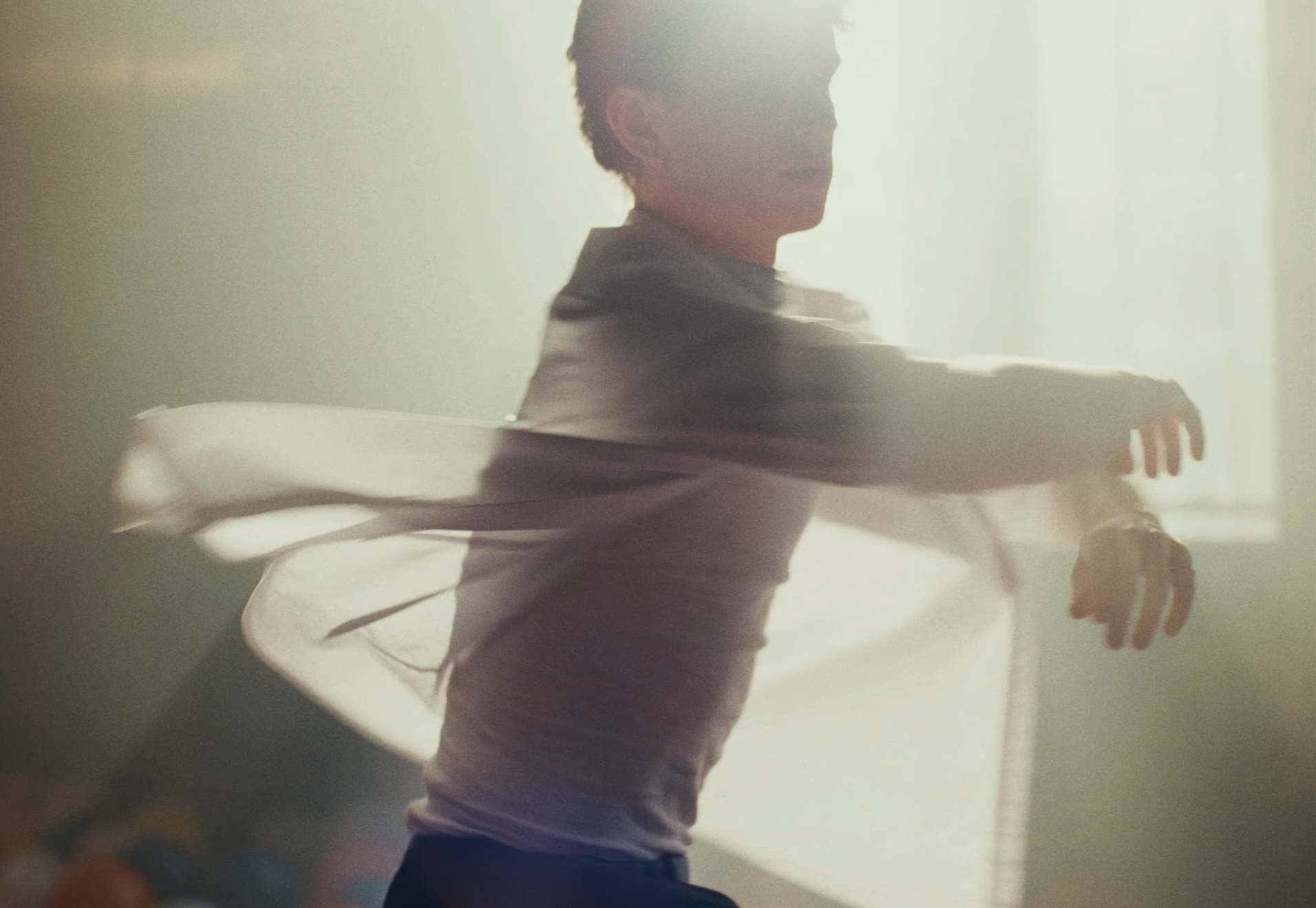 A person in a white shirt is spinning bands around their arms in a brightly lit room.