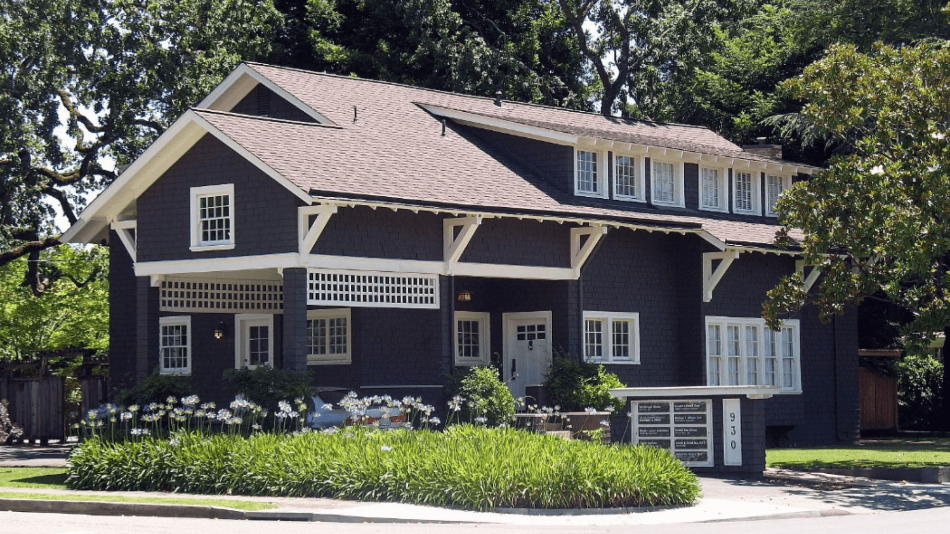 Wasserman House at 930 Mendocino Avenue, brown building with white trim, surrounded by green plants and grass on a sunny day.