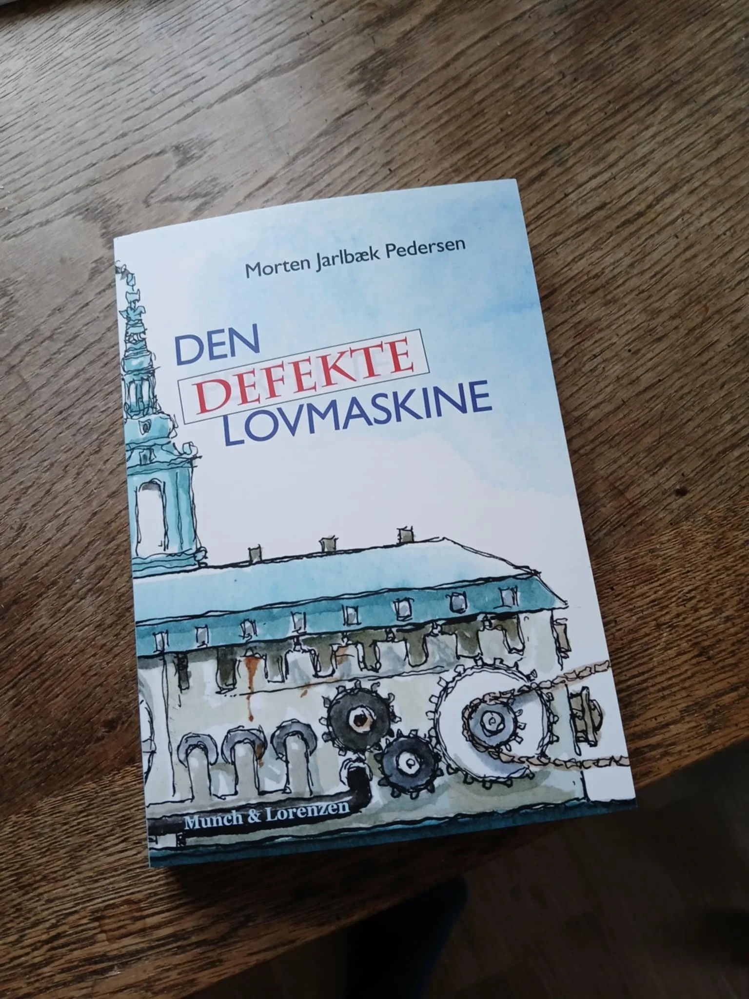 Billede af bogen "Den defekte lovmaskine" af Morten Jarlbæk Pedersen